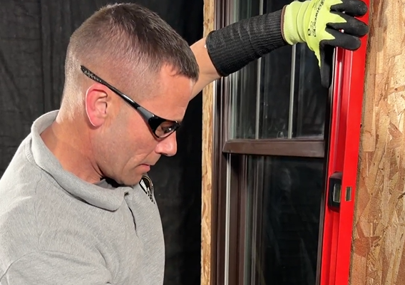 Window and door technician checking a window with a level