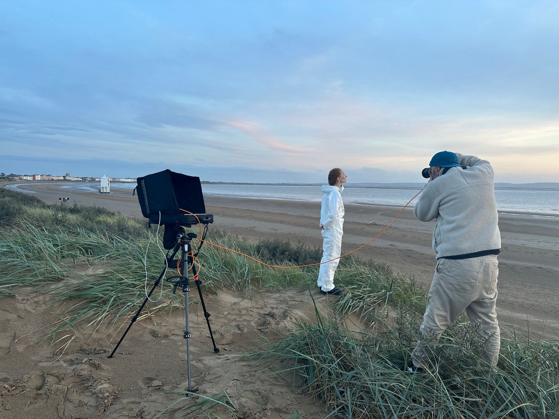 A person taking a picture of a woman on a beach.