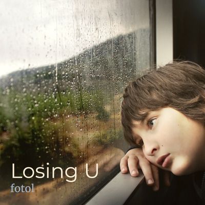 An image of a sad boy looking out of a window.