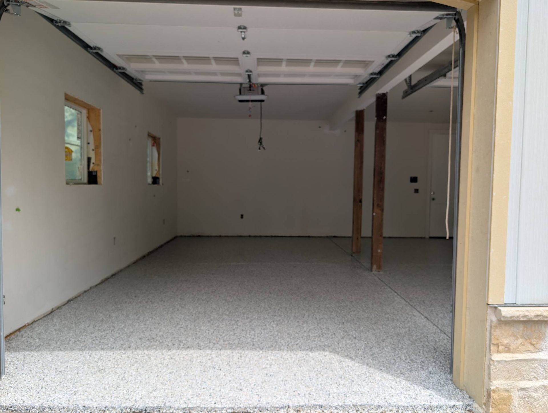 Empty unfinished garage with white walls, gray floor, and open doorway.