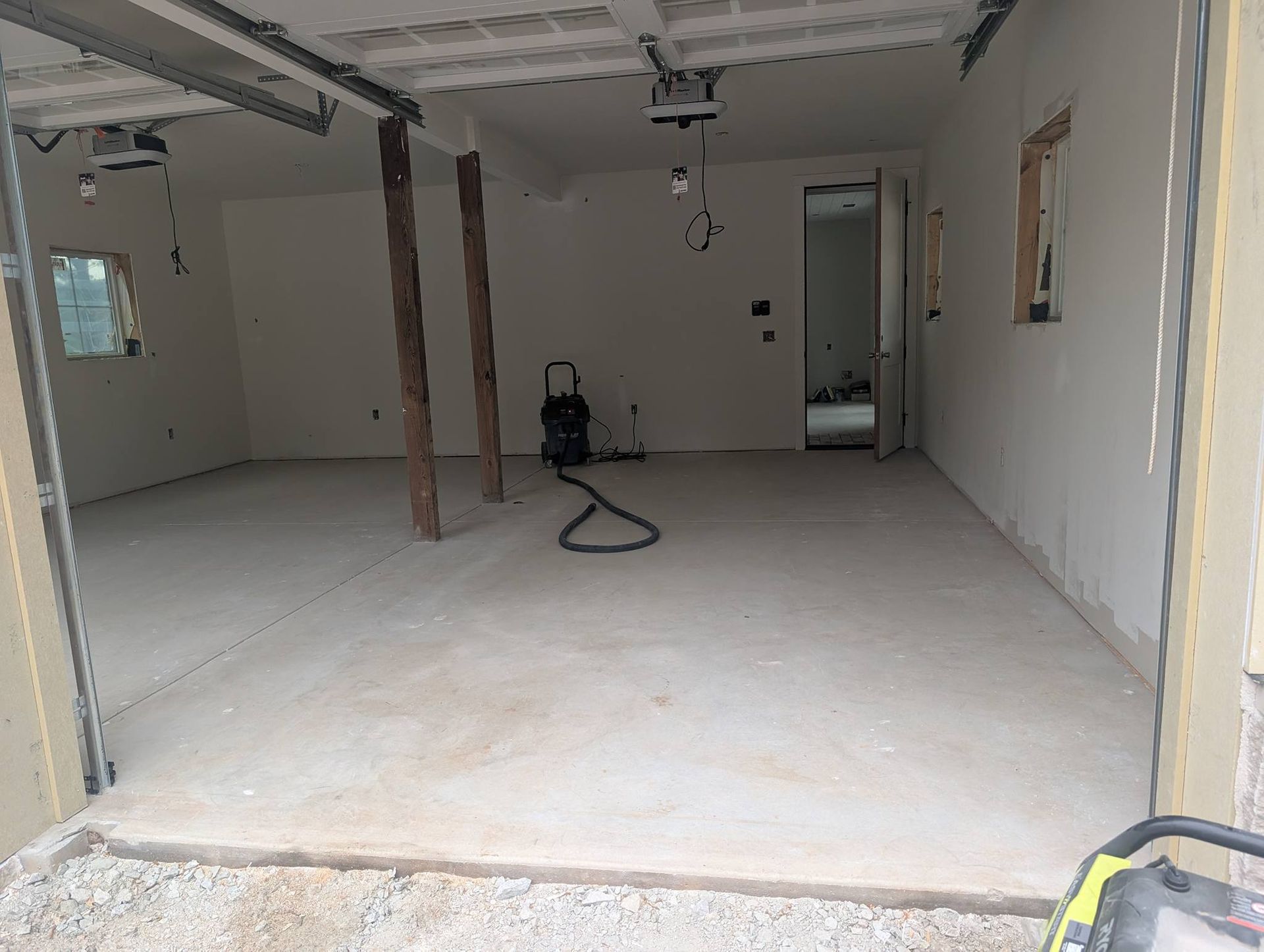 Empty unfinished garage interior with concrete floor and a vacuum cleaner near the back wall