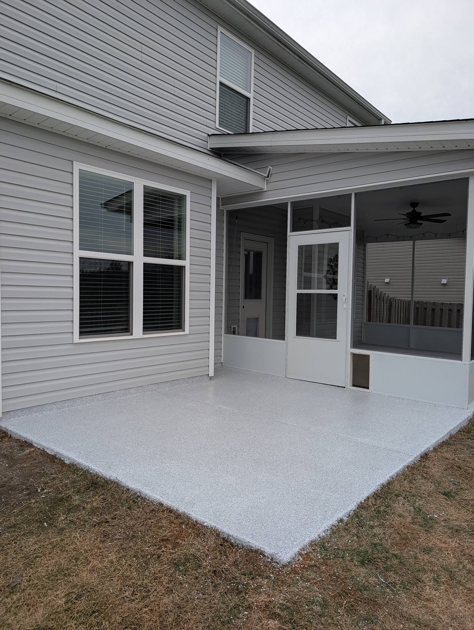 Rear patio of a gray house with white-framed windows and a covered porch ceiling fan