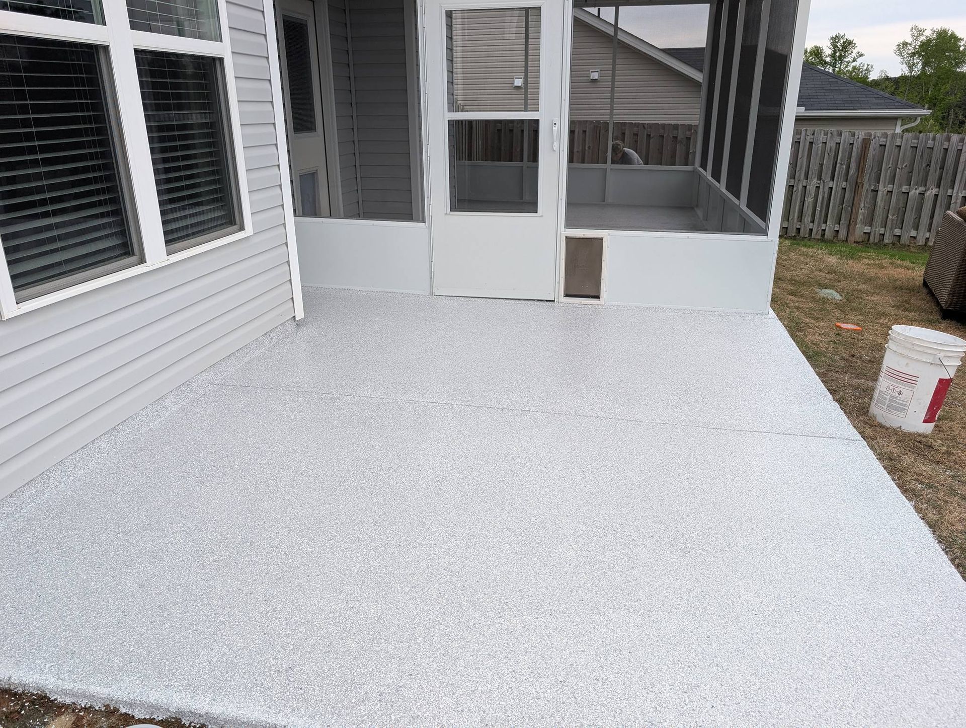 Freshly resurfaced white patio beside a screened porch and house siding