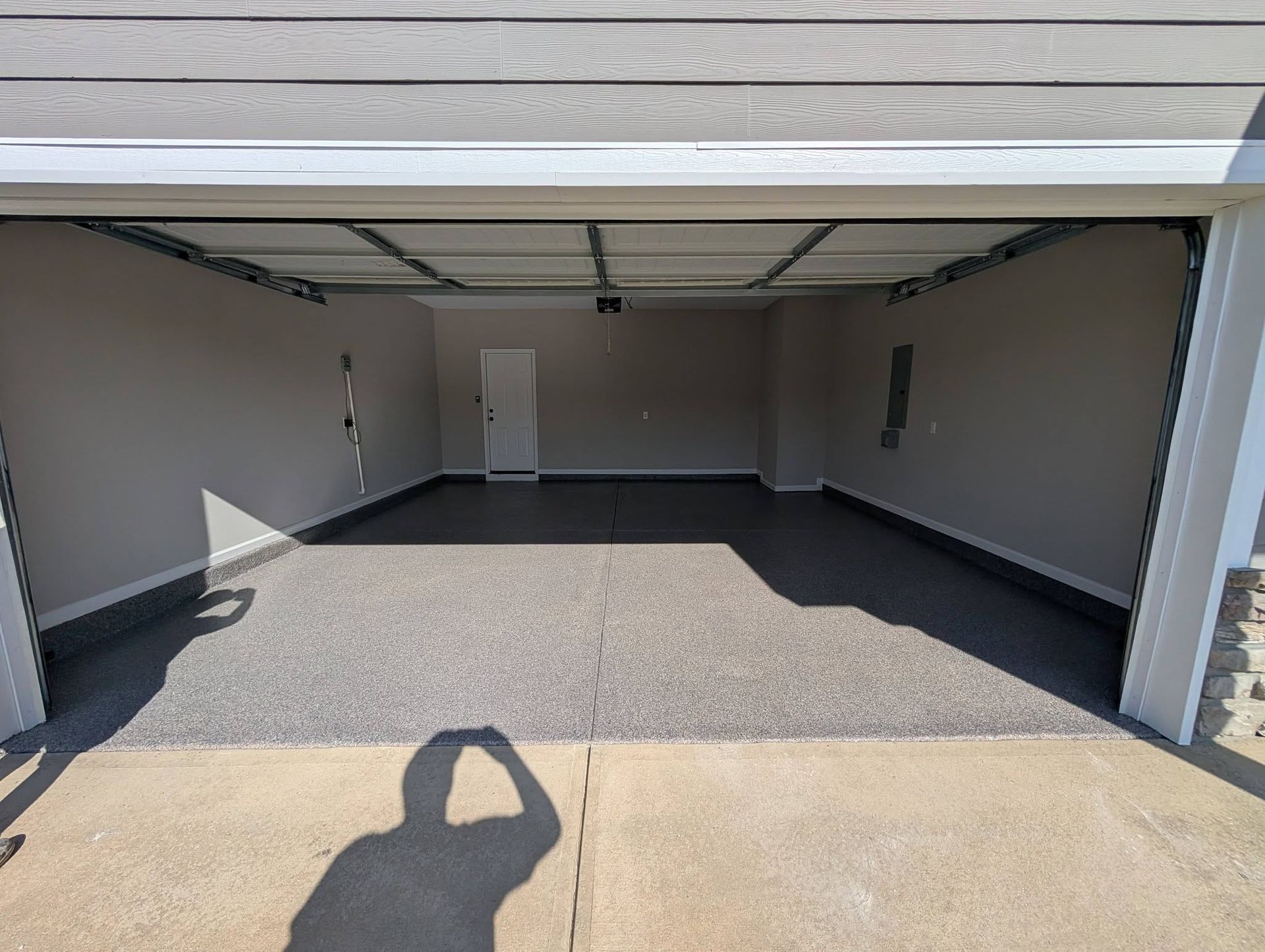 Open garage with white walls, gray floor, and a closed door at the back.