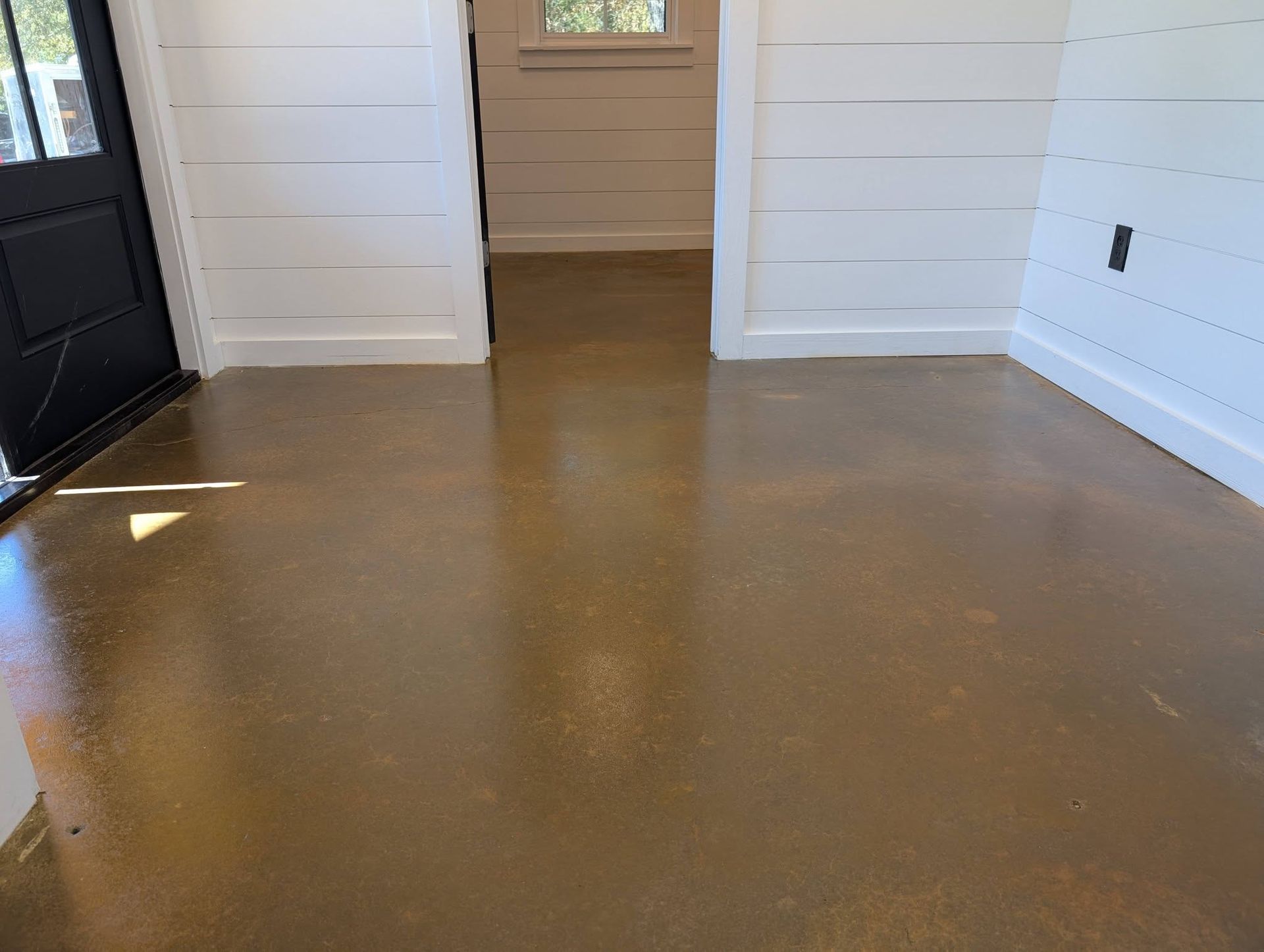 Empty room with brown floor, white walls, and an open doorway to a hallway