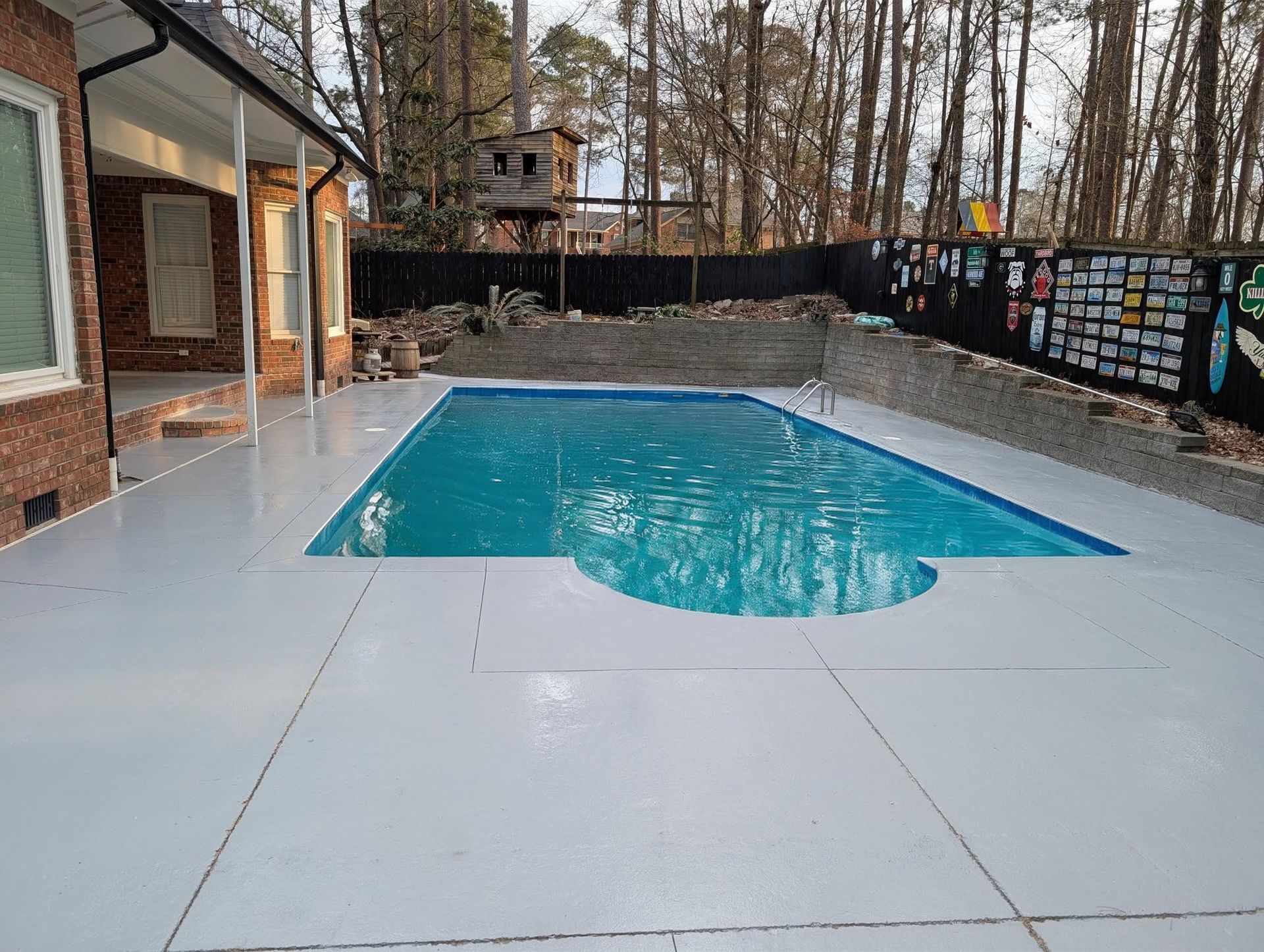 Backyard swimming pool with a white deck and wooded fence surrounding it