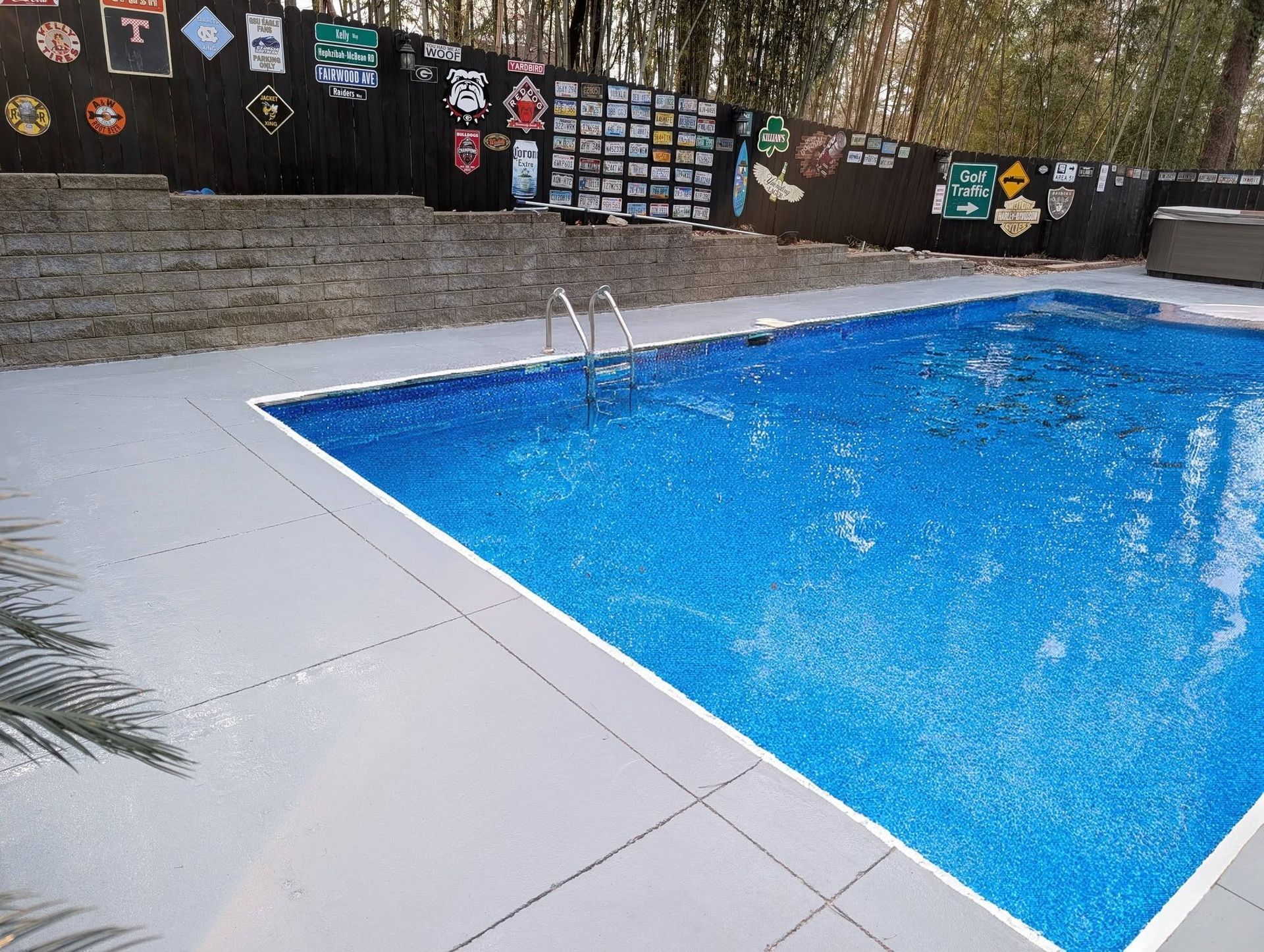 Blue outdoor swimming pool with a small fountain and a decorated wall in the background