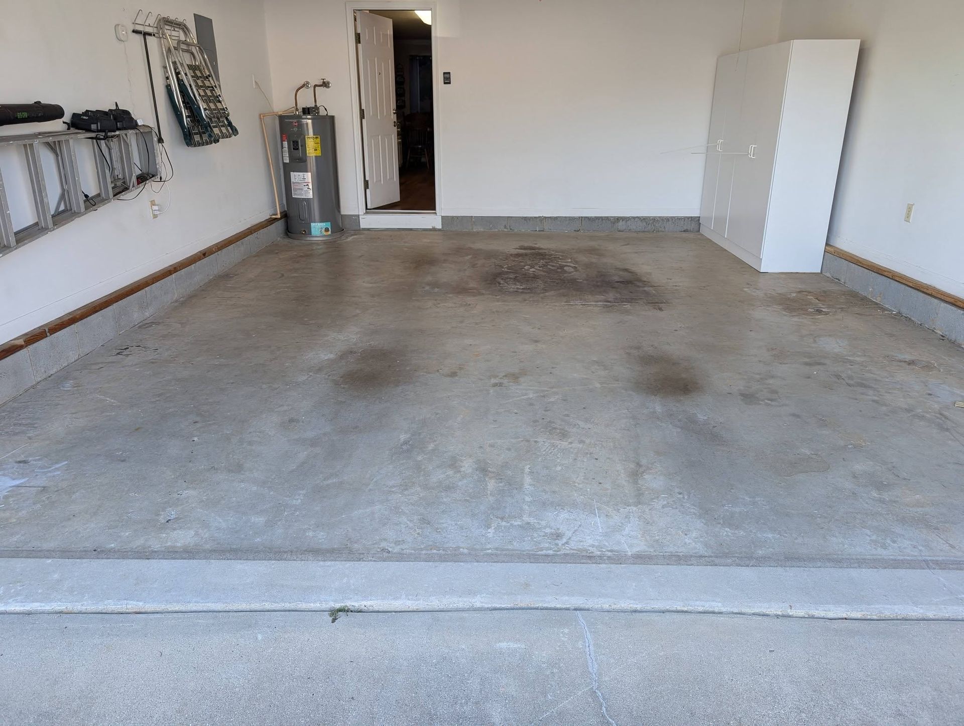 Empty garage with bare concrete floor, white walls, and a door at the far end.