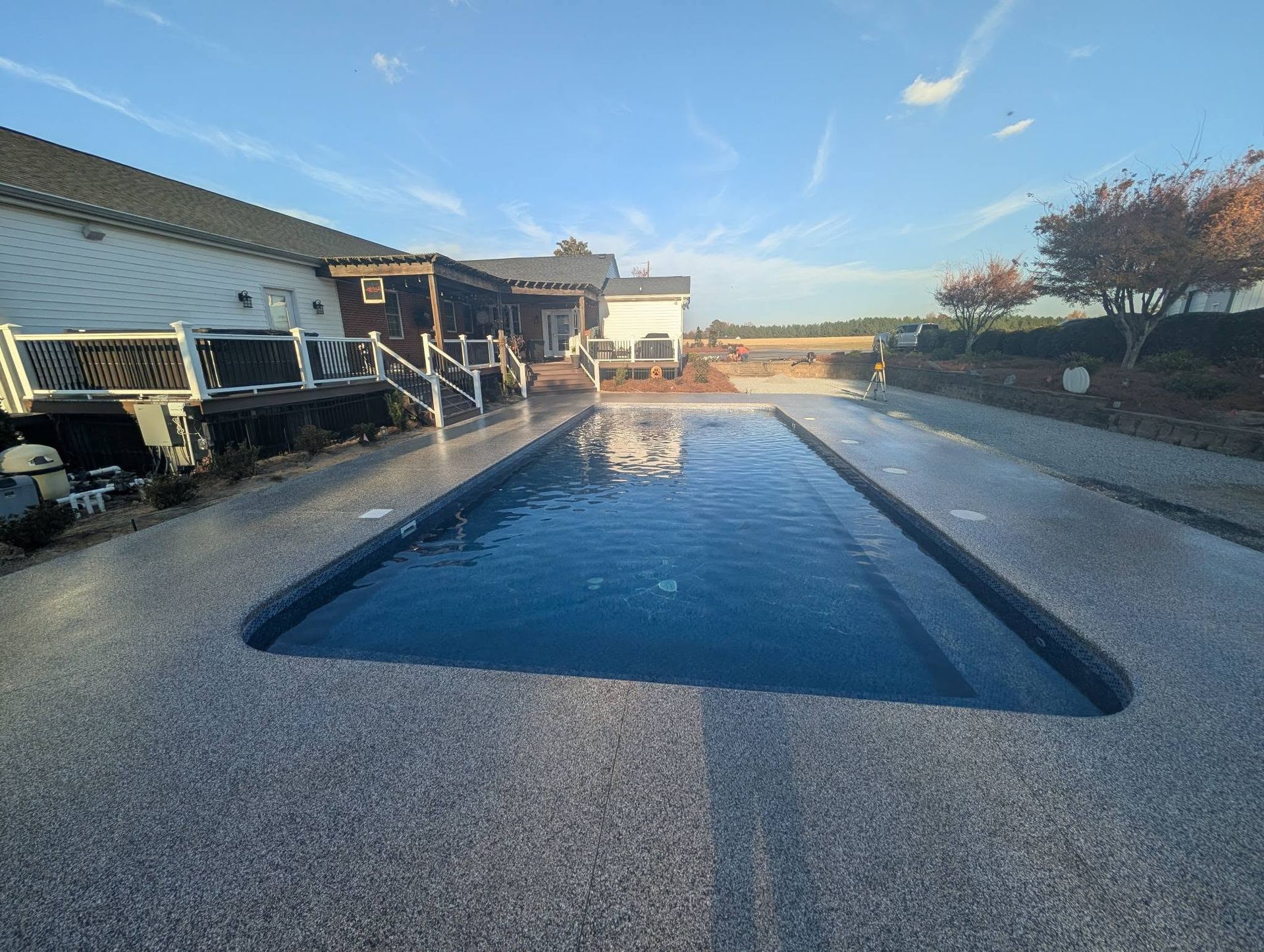 Rectangular outdoor swimming pool with blue water beside a house on a sunny day