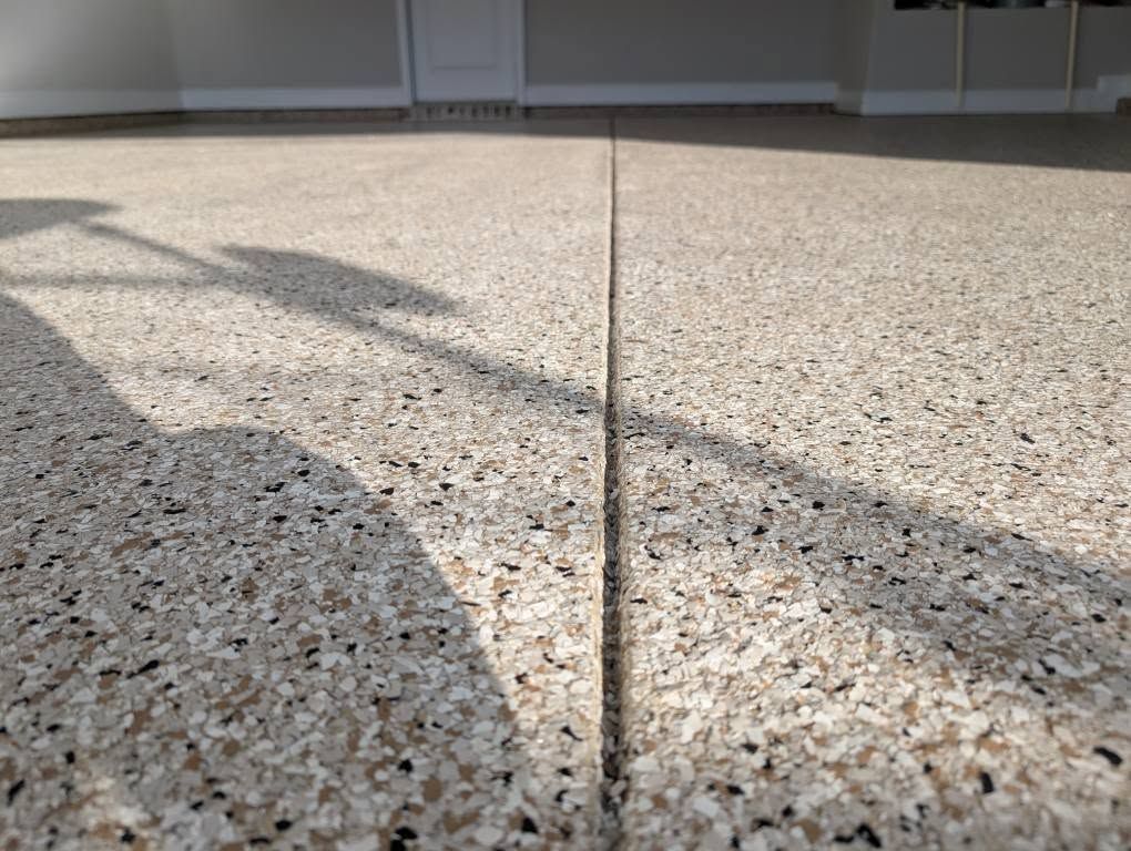 Sunlit concrete patio with a long shadow and a central expansion joint