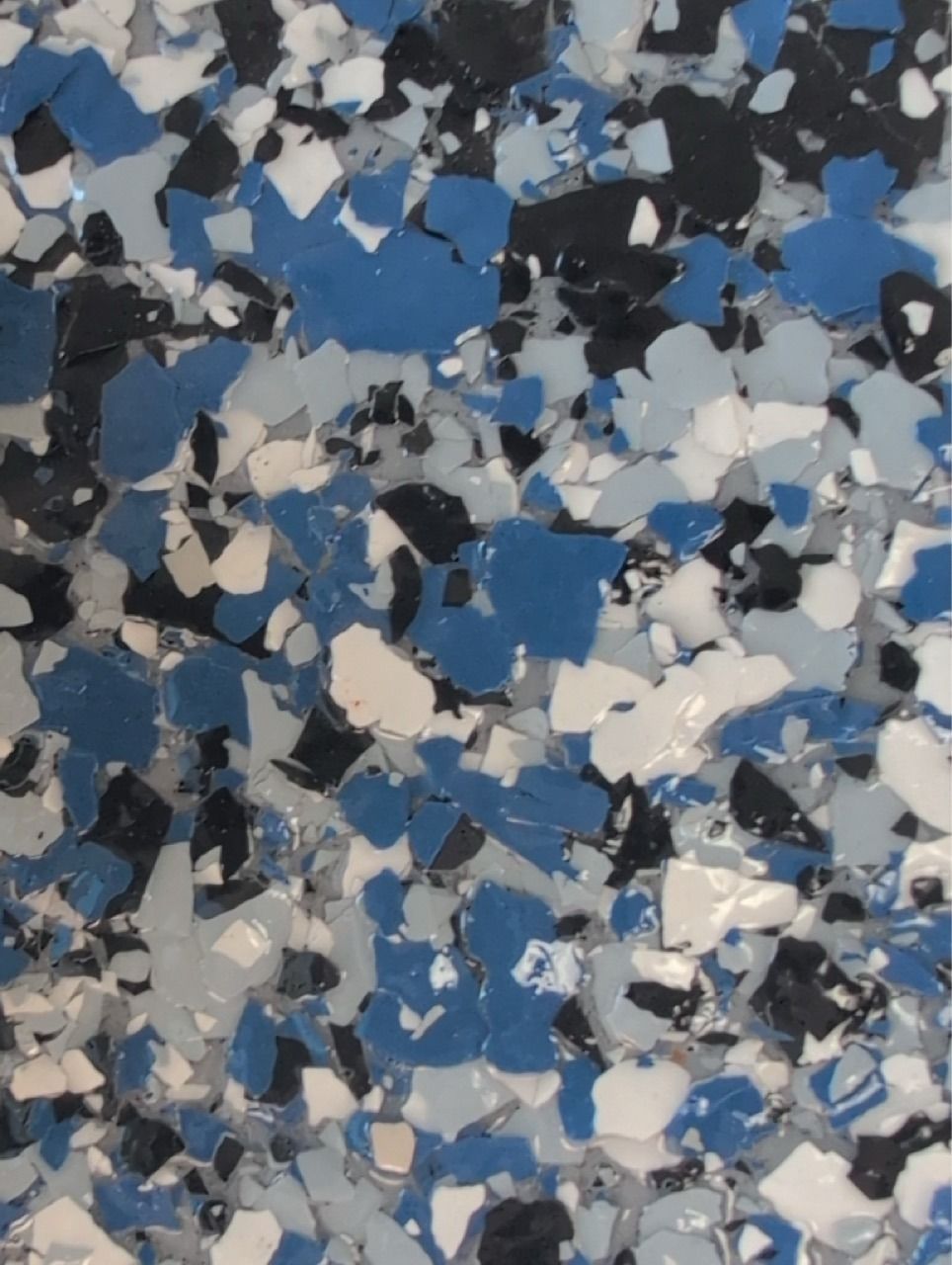 Abstract blue, black, gray, and white speckled paint pattern.