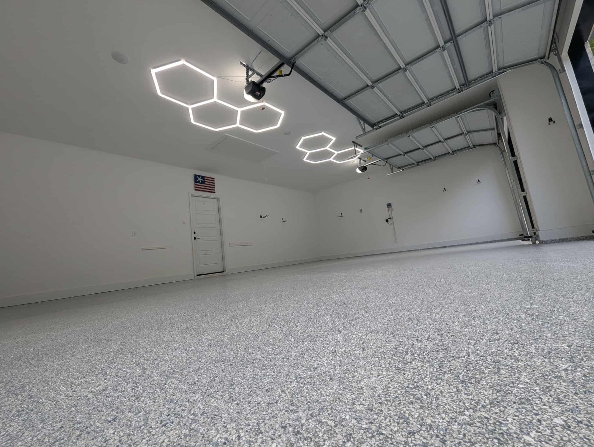 Empty white warehouse with hexagonal ceiling lights and a speckled gray floor
