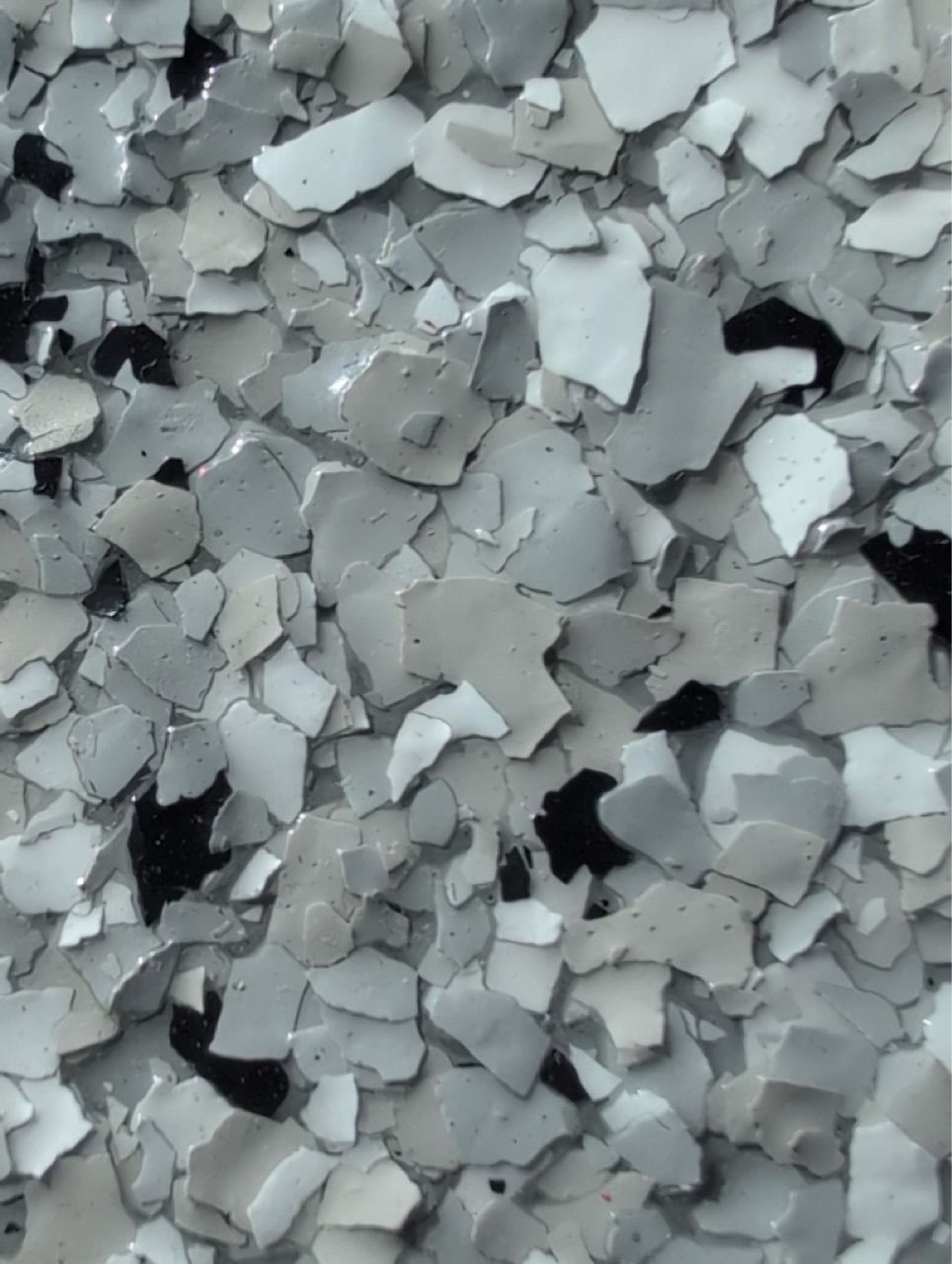 Close-up of light gray broken flakes or chips piled together, with a rough textured surface