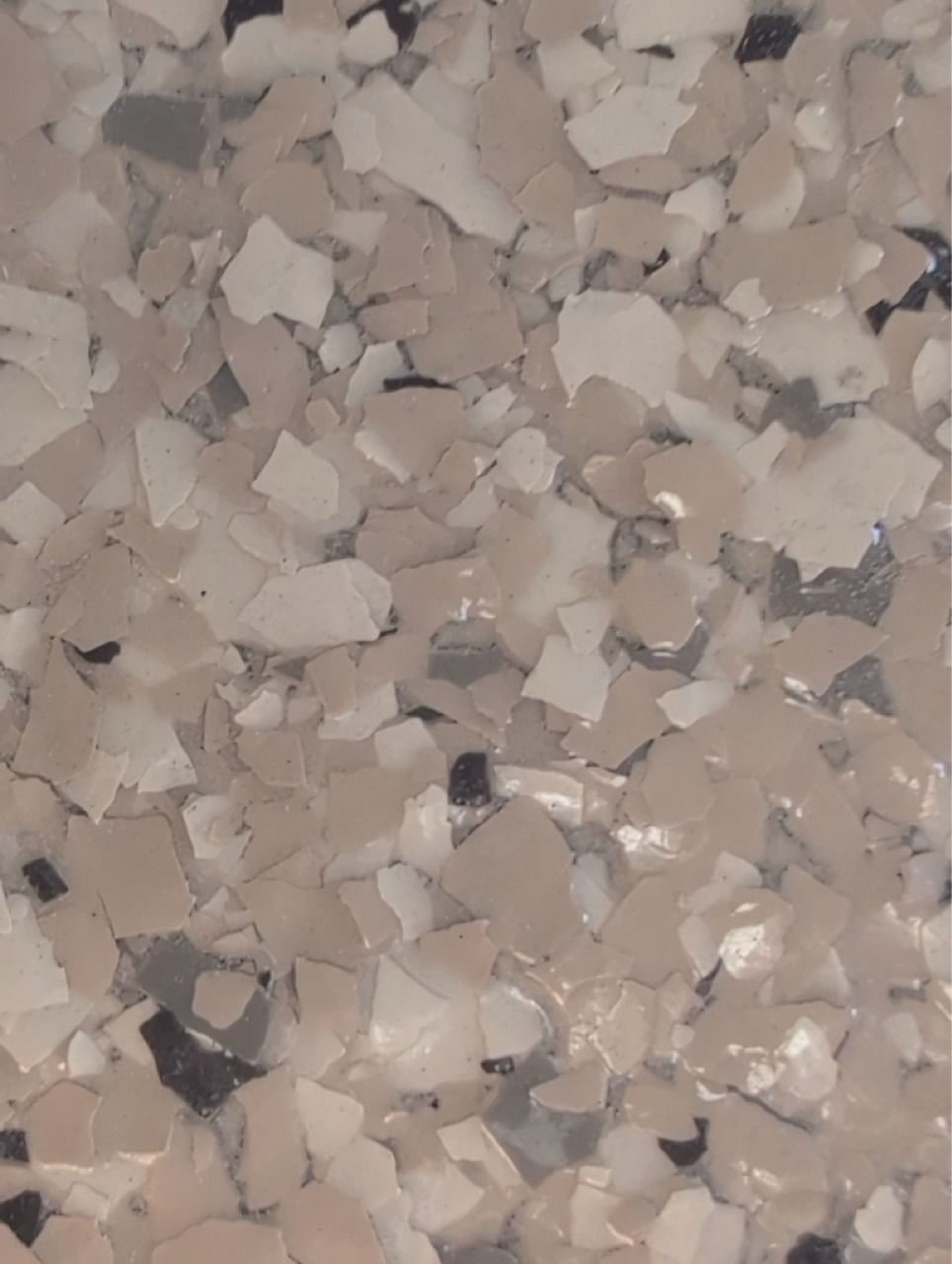 Close-up of beige and gray speckled stone or terrazzo surface with small chips.