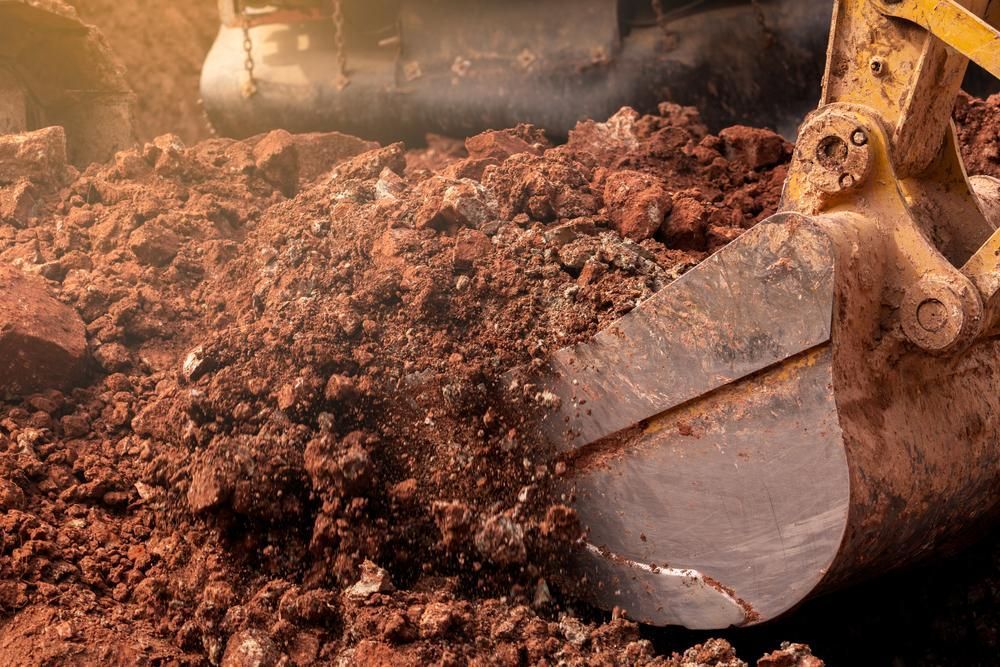 A Bulldozer Is Digging A Hole In The Ground — Glen Tier Bobcat & Truck Hire In Woree, QLD