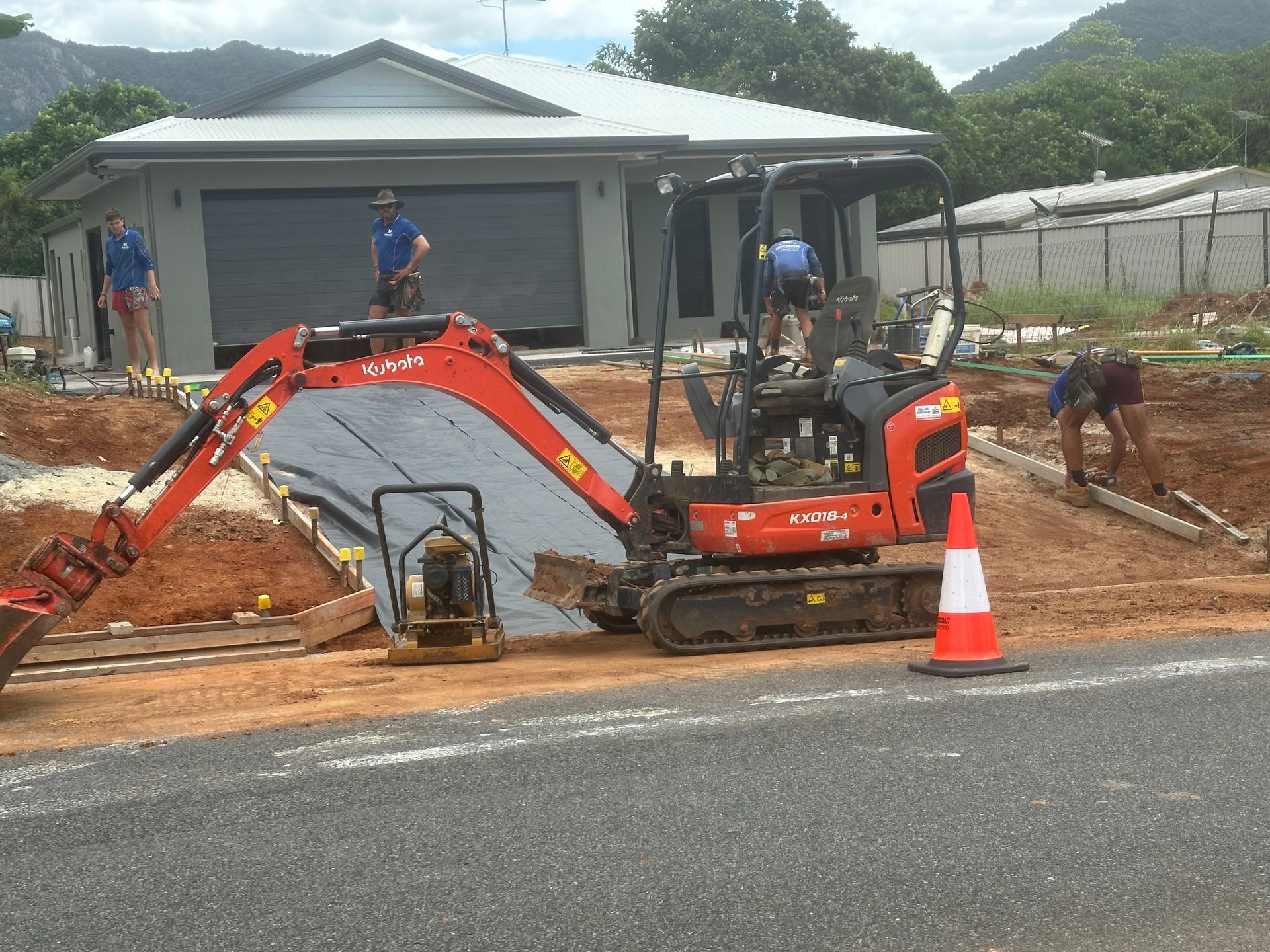 A Yellow Excavator Is Digging A Hole In The Ground — Glen Tier Bobcat & Truck Hire In Innisfail, QLD