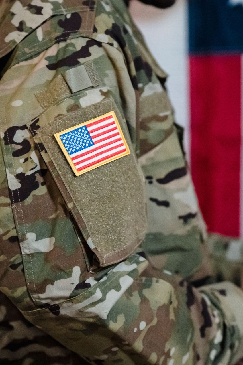 Close-up of a camouflage military uniform sleeve with an American flag patch.