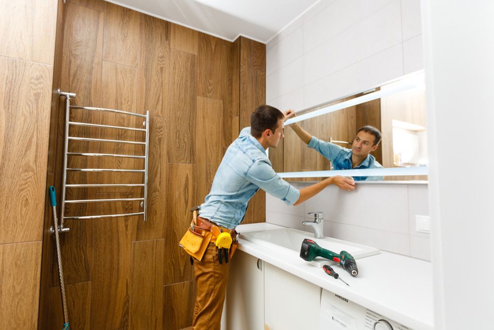Man Setting Up the Vanity Mirror in the Bathroom — Bathroom Renovation in Gladstone Region, QLD