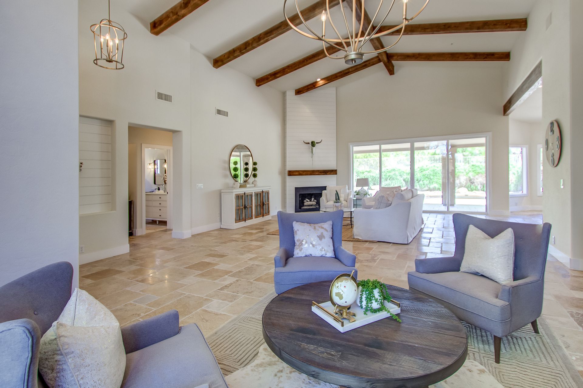 A living room with a round coffee table , chairs , and a fireplace.