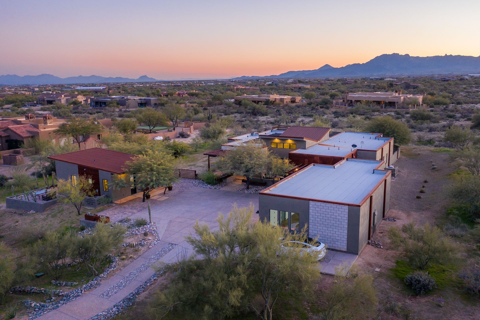 An aerial view of a house in the desert with mountains in the background.