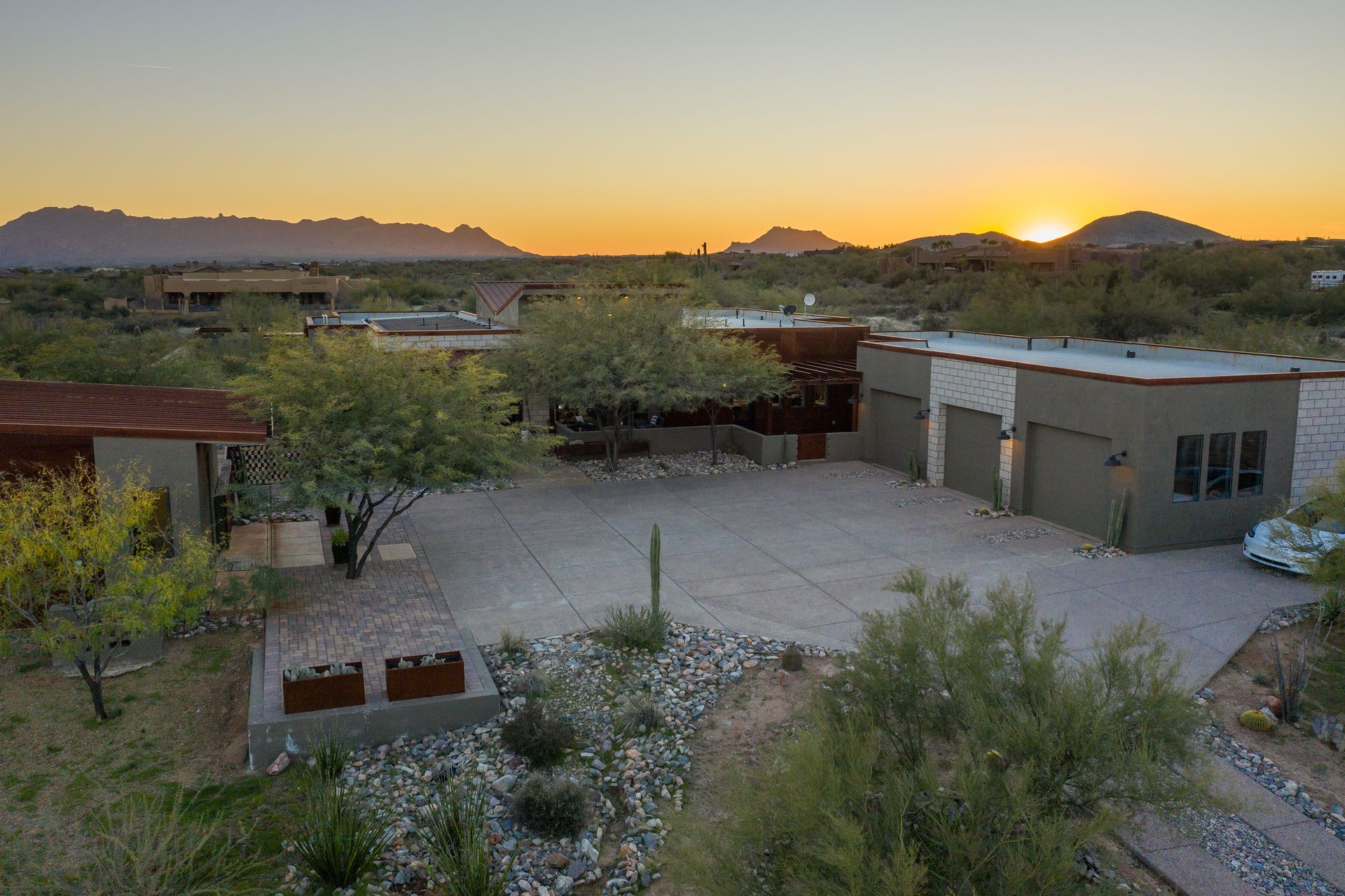 An aerial view of a house in the desert at sunset.