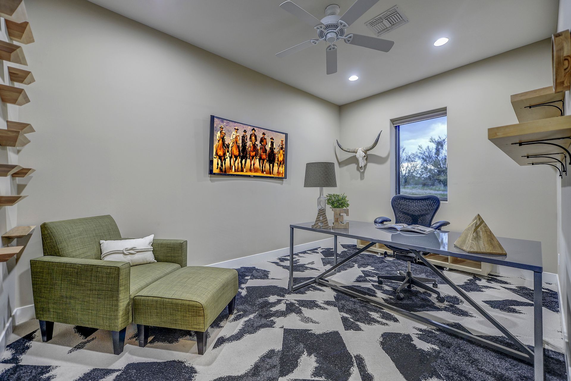 A home office with a desk , chair , ottoman and a painting on the wall.