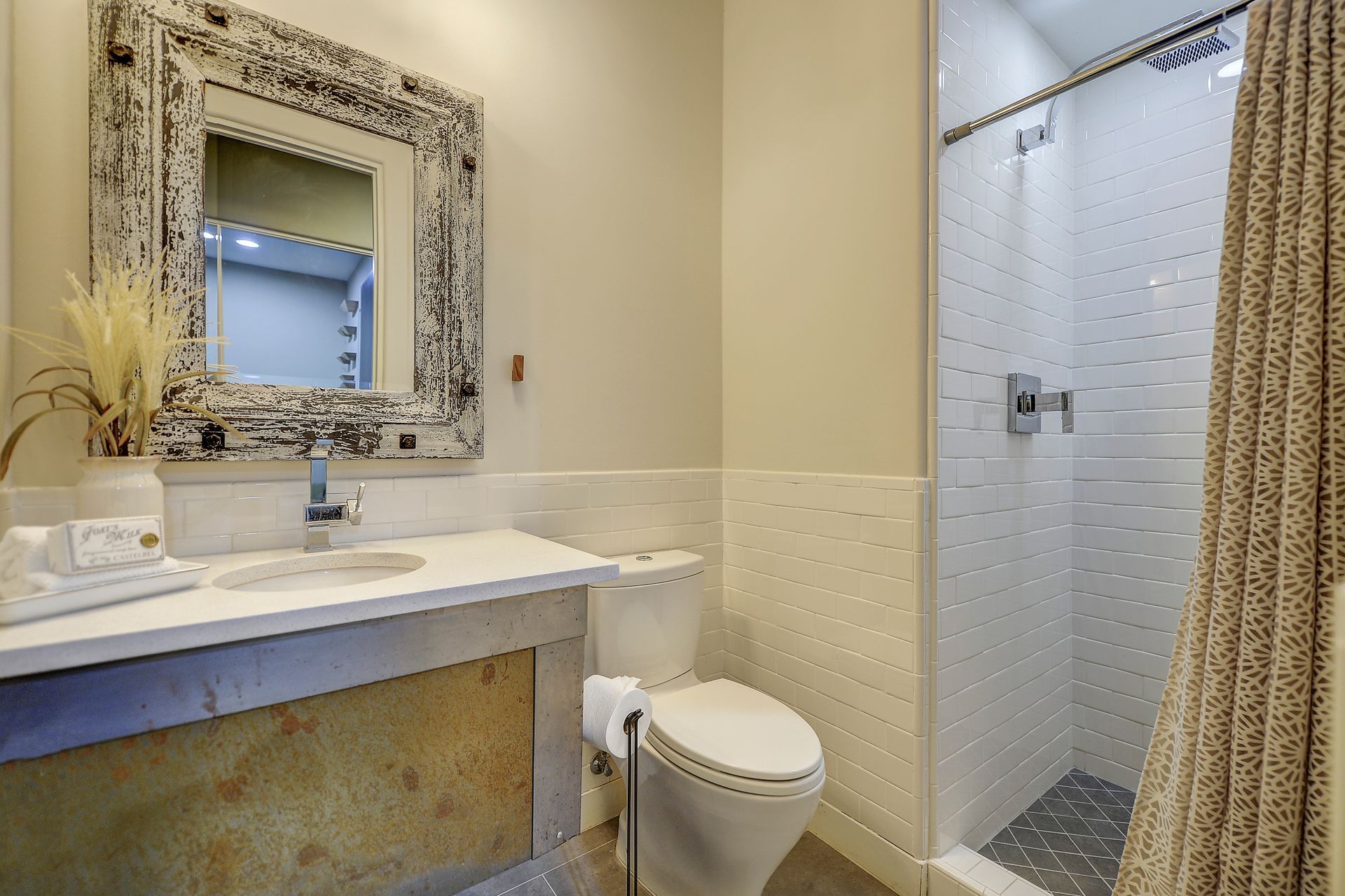 A bathroom with a toilet , sink , mirror and shower.