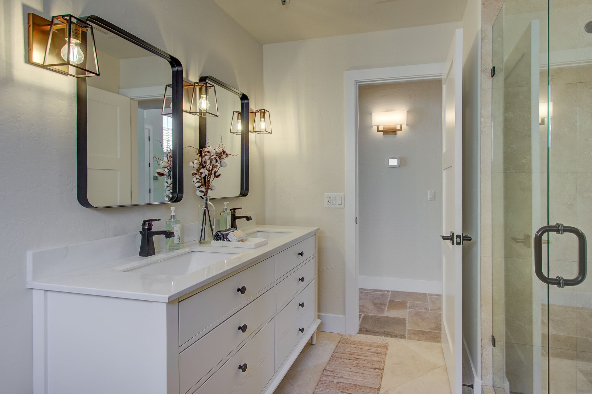 A bathroom with two sinks , two mirrors and a walk in shower.