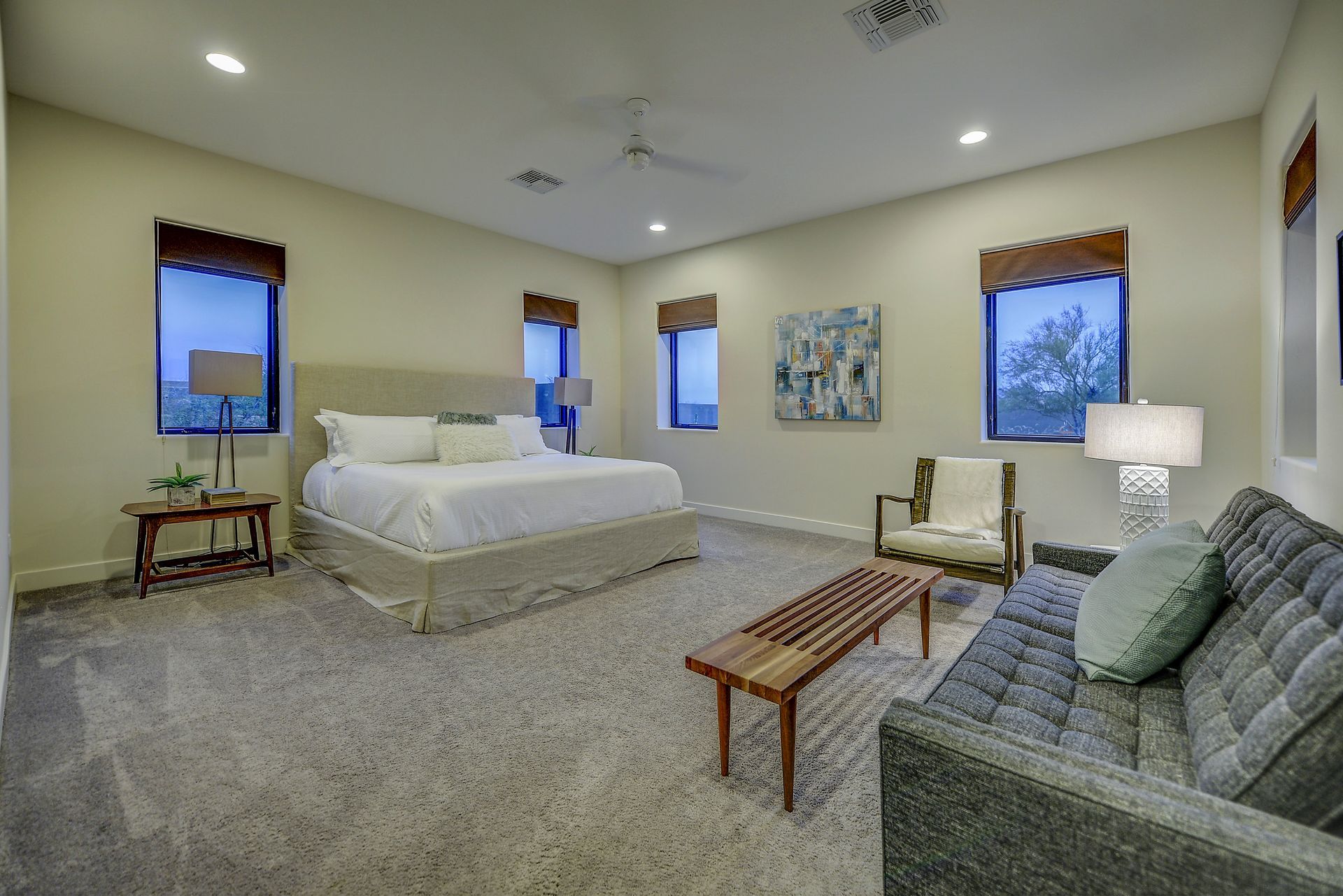 A bedroom with a king size bed , a couch , chairs and a coffee table.