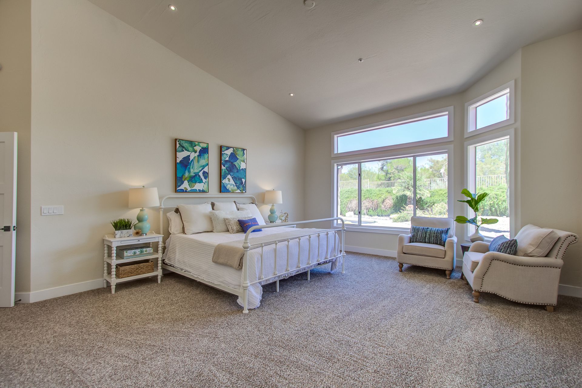 A bedroom with a bed , chair , nightstand , and large windows.