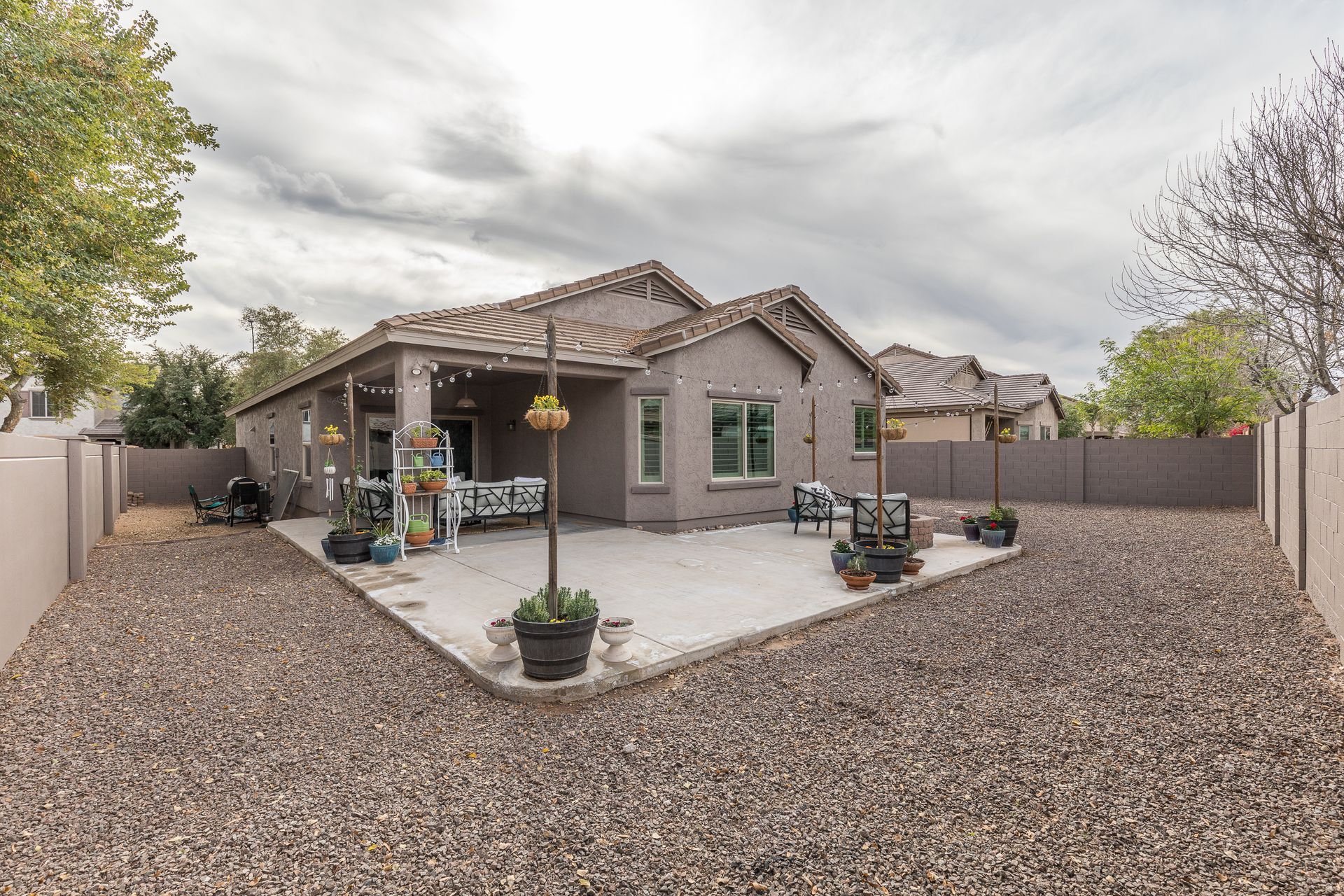A house with a patio and a gravel driveway in front of it.
