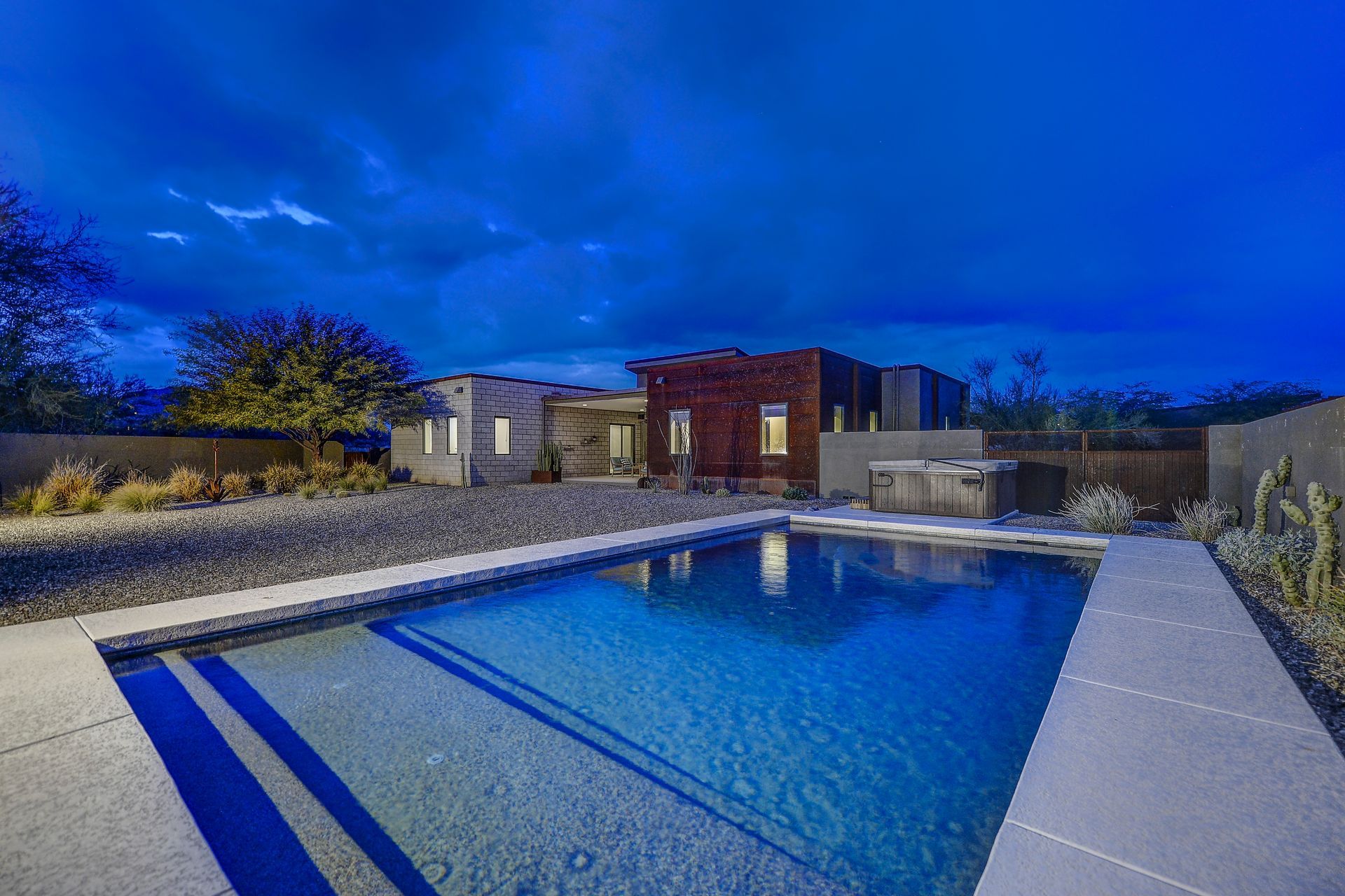 A large swimming pool in front of a house at night.