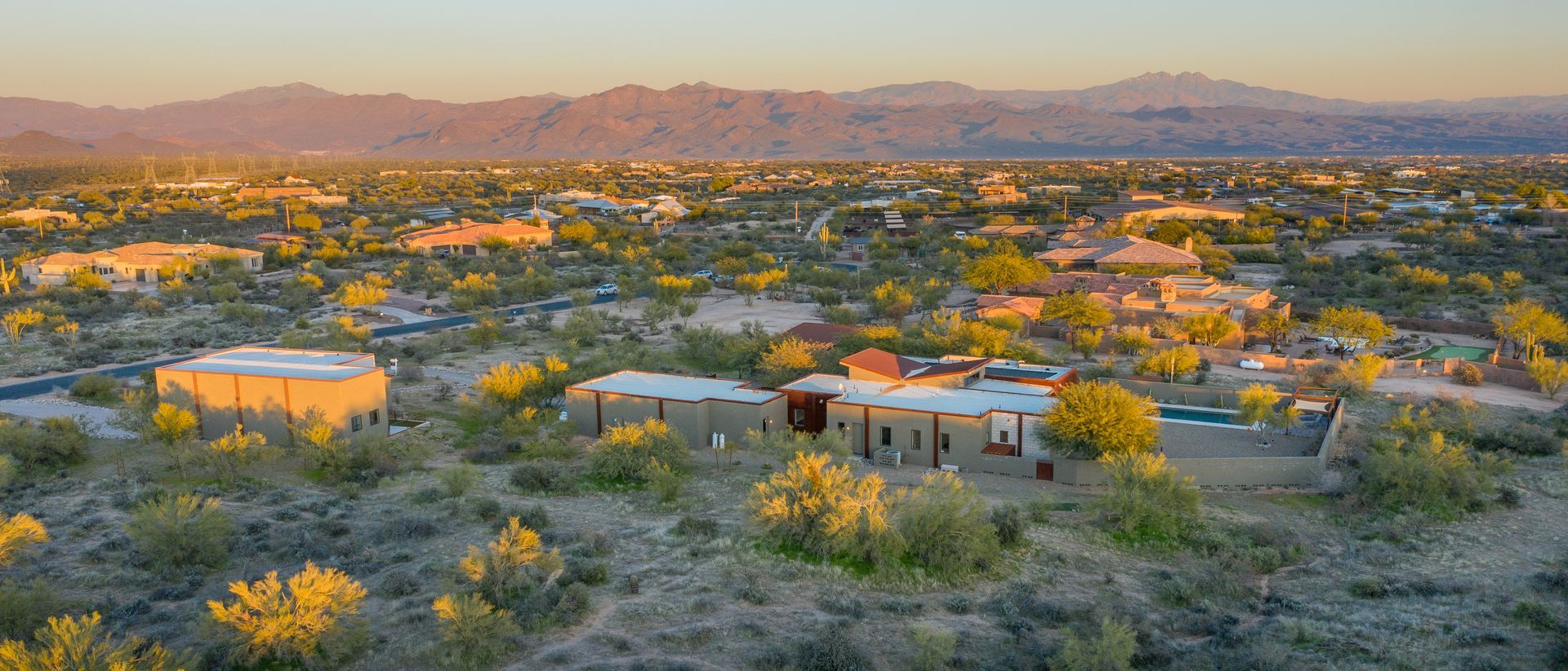 An aerial view of a city with mountains in the background at sunset.
