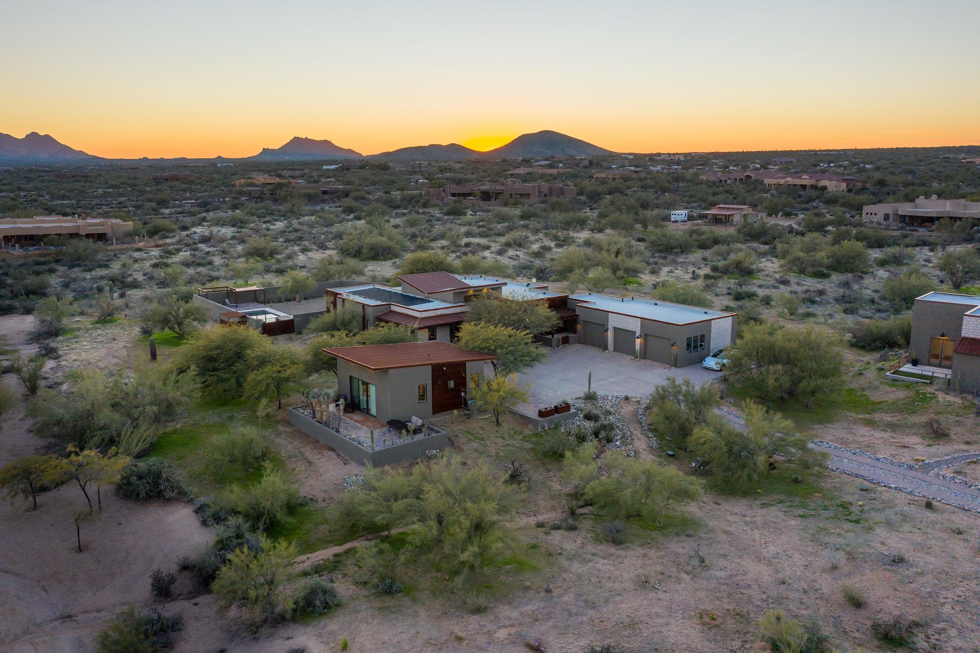 An aerial view of a house in the desert at sunset.