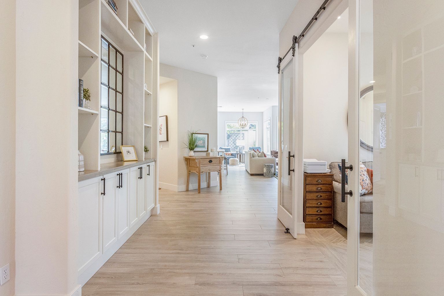 A hallway in a house with sliding barn doors leading to a living room.