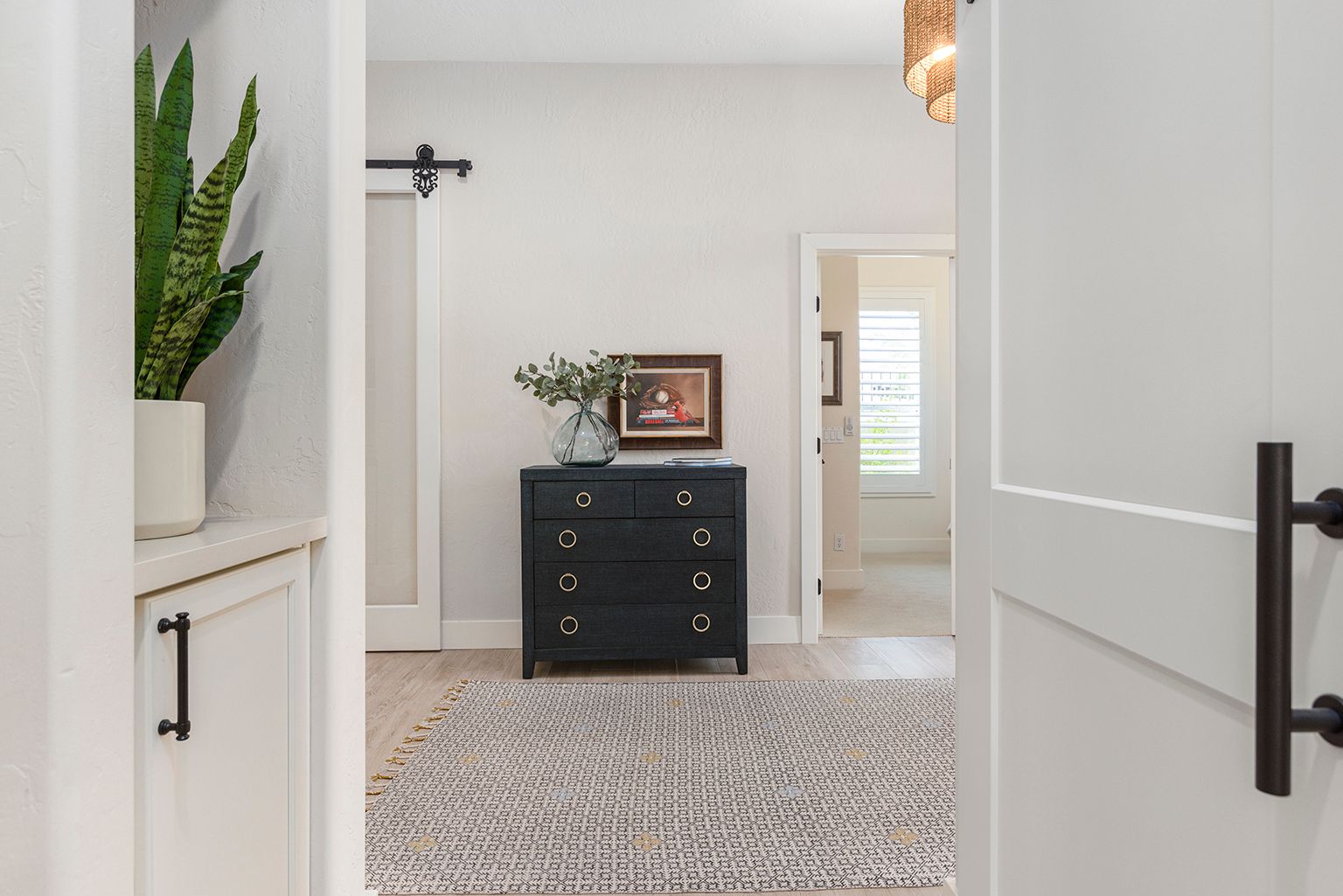 A hallway in a house with a dresser and a rug.