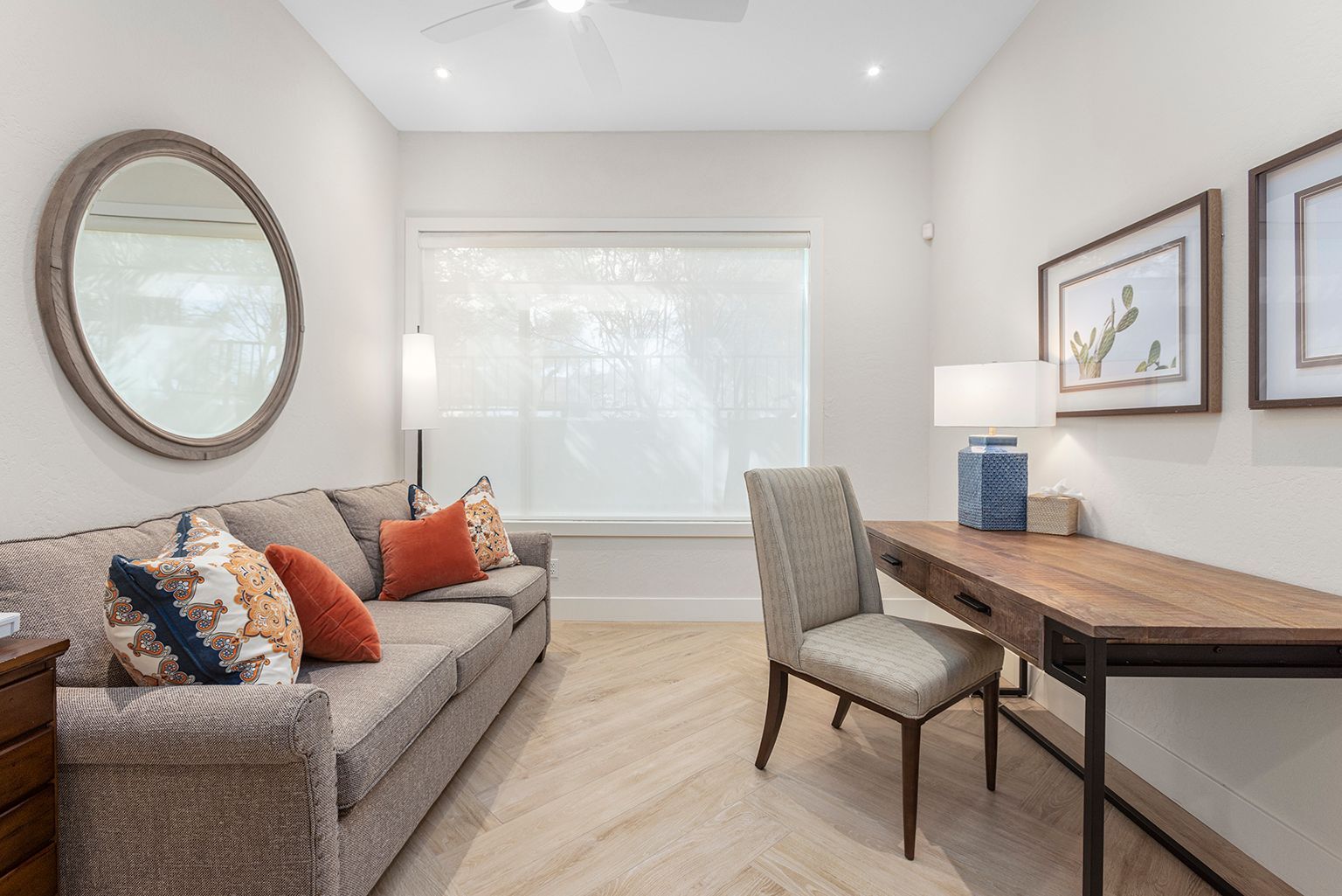 A living room with a couch , chair , desk and mirror.