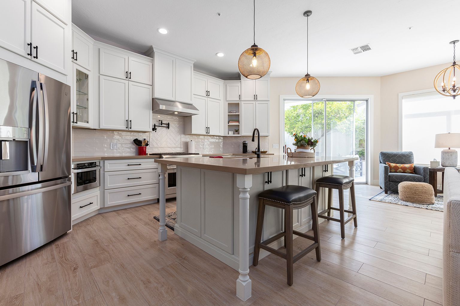 A kitchen with white cabinets and stainless steel appliances and a large island.