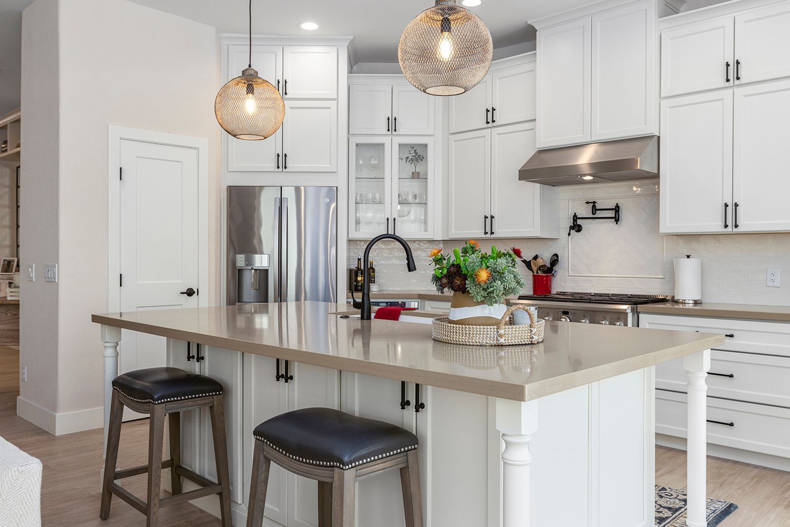 A kitchen with white cabinets , stainless steel appliances , and a large island.