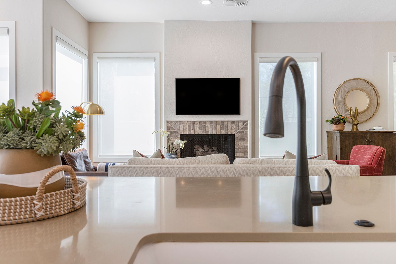 A kitchen with a sink , faucet , television and fireplace.