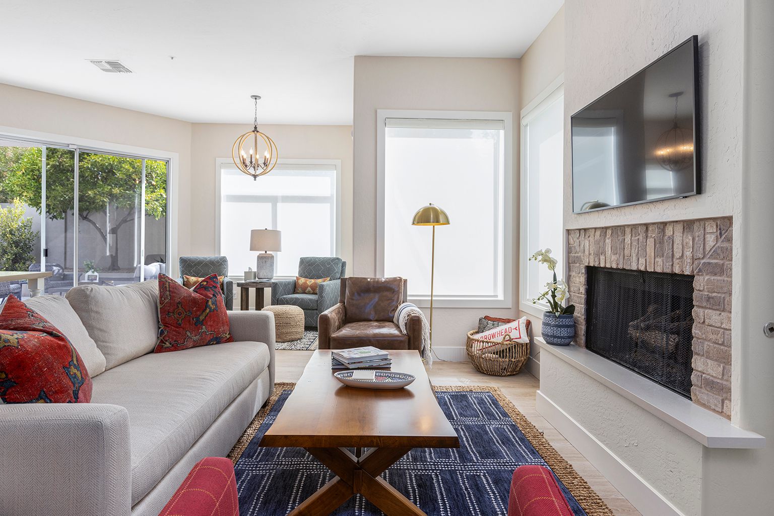 A living room with a couch , chair , coffee table , fireplace and television.