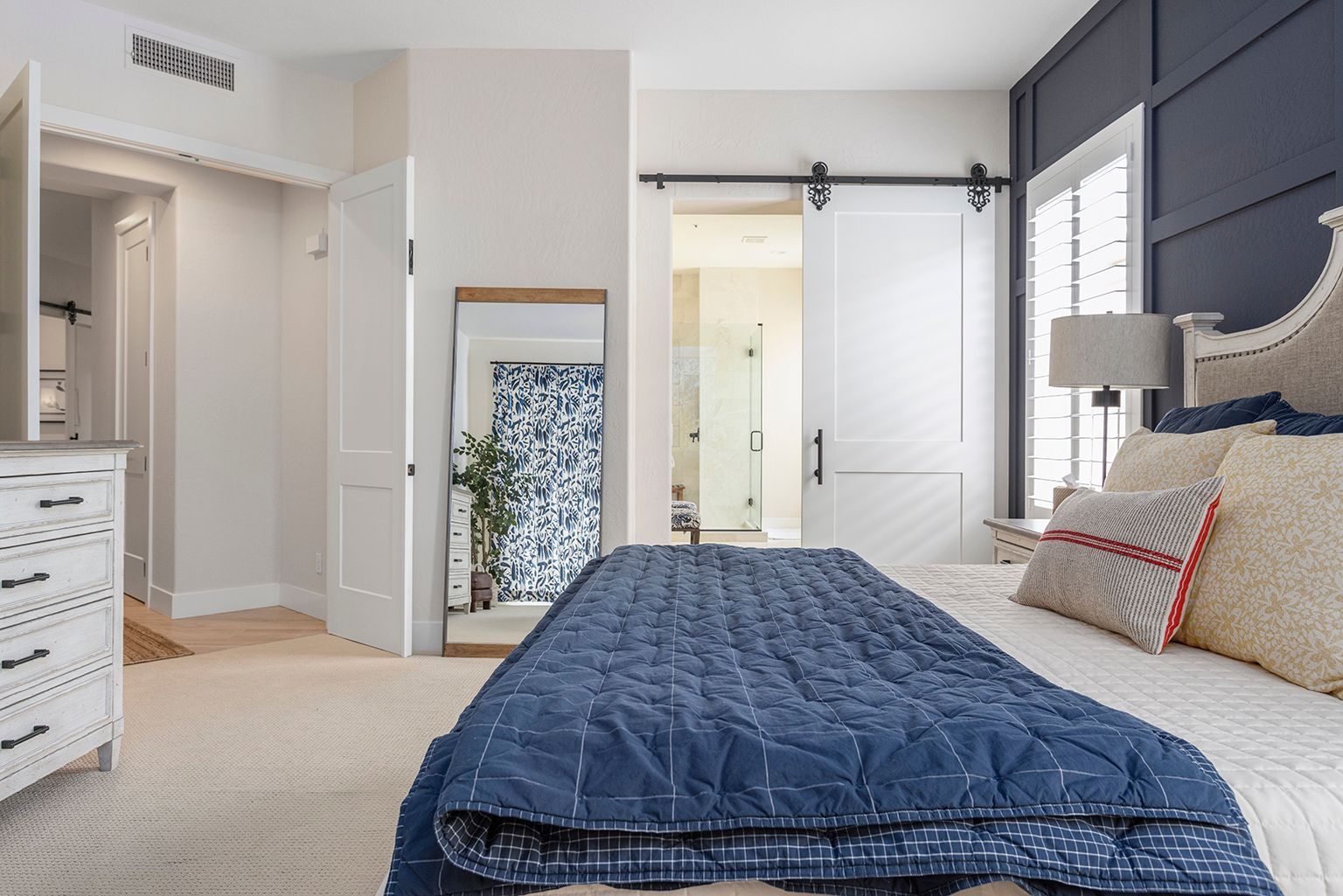 A bedroom with a bed , dresser , mirror and sliding barn doors.