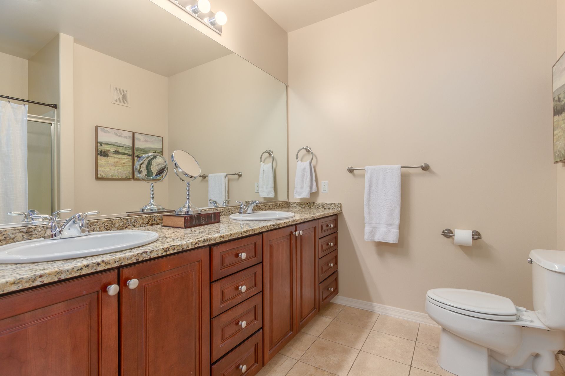 A bathroom with two sinks , a toilet and a mirror.