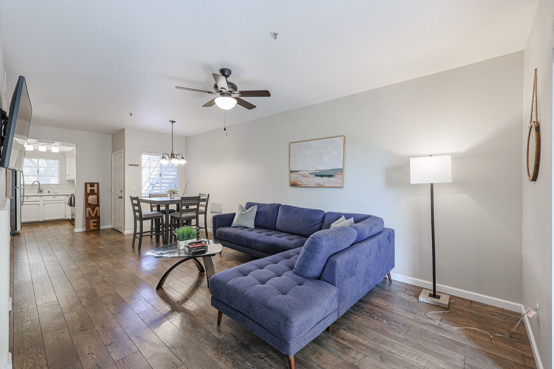 A living room with a blue sectional couch and a ceiling fan
