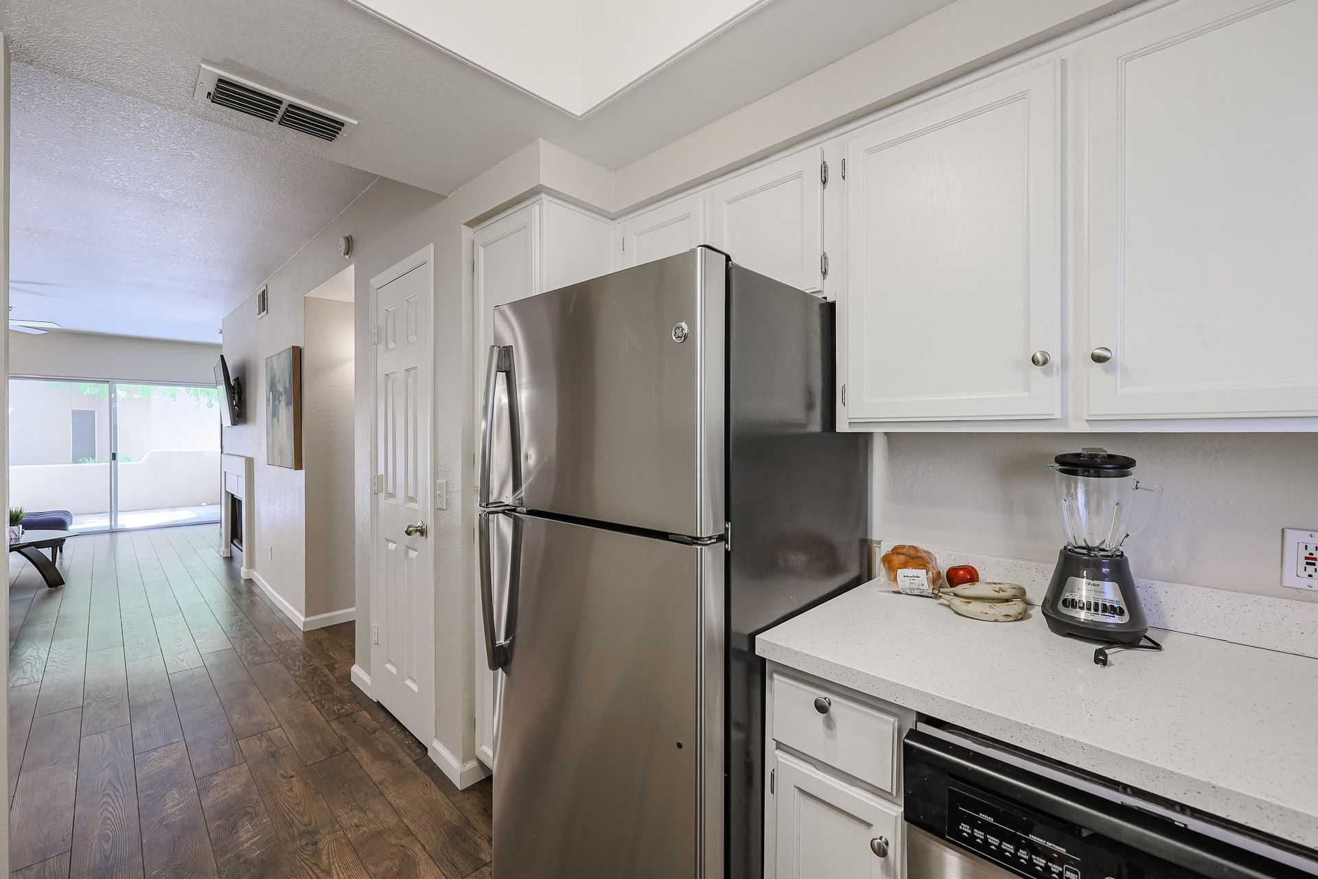 A kitchen with a stainless steel refrigerator and a blender on the counter.