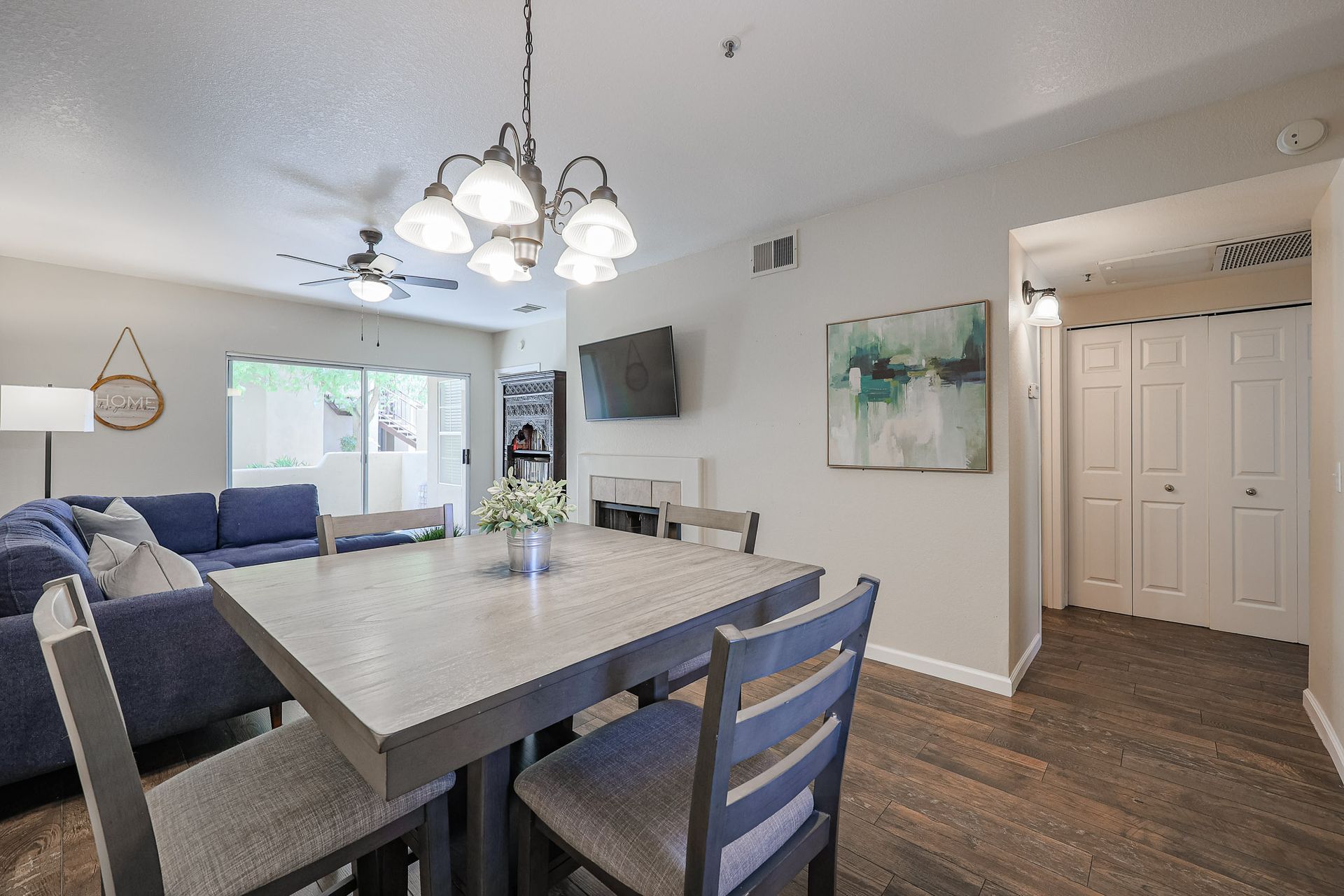 A living room with a dining table and chairs and a ceiling fan.