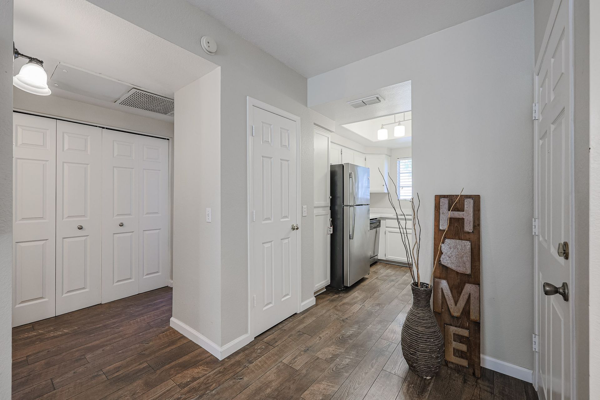 A hallway in a house with hardwood floors and a sign that says `` home ''.