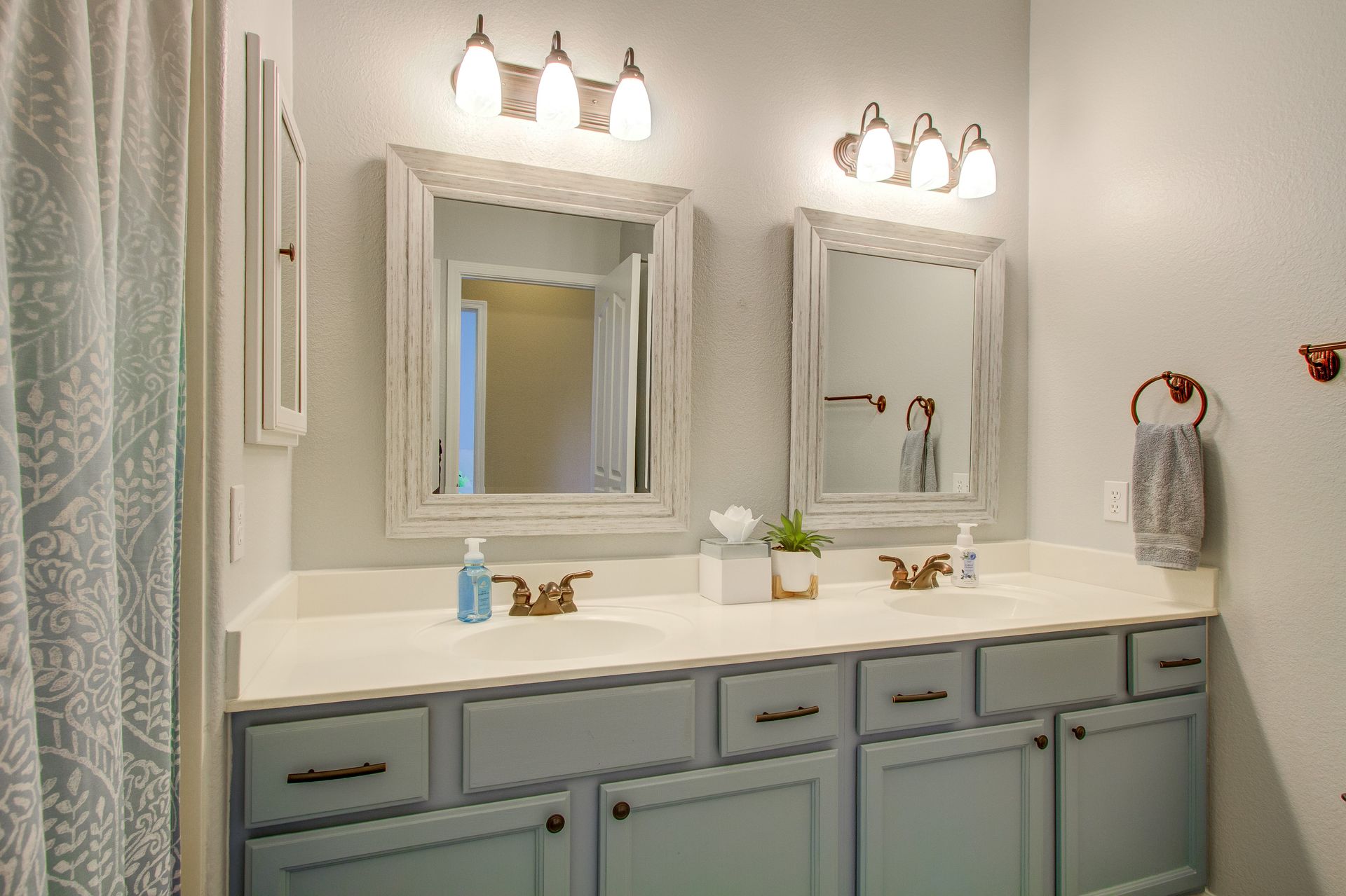 A bathroom with two sinks , two mirrors , and a shower curtain.
