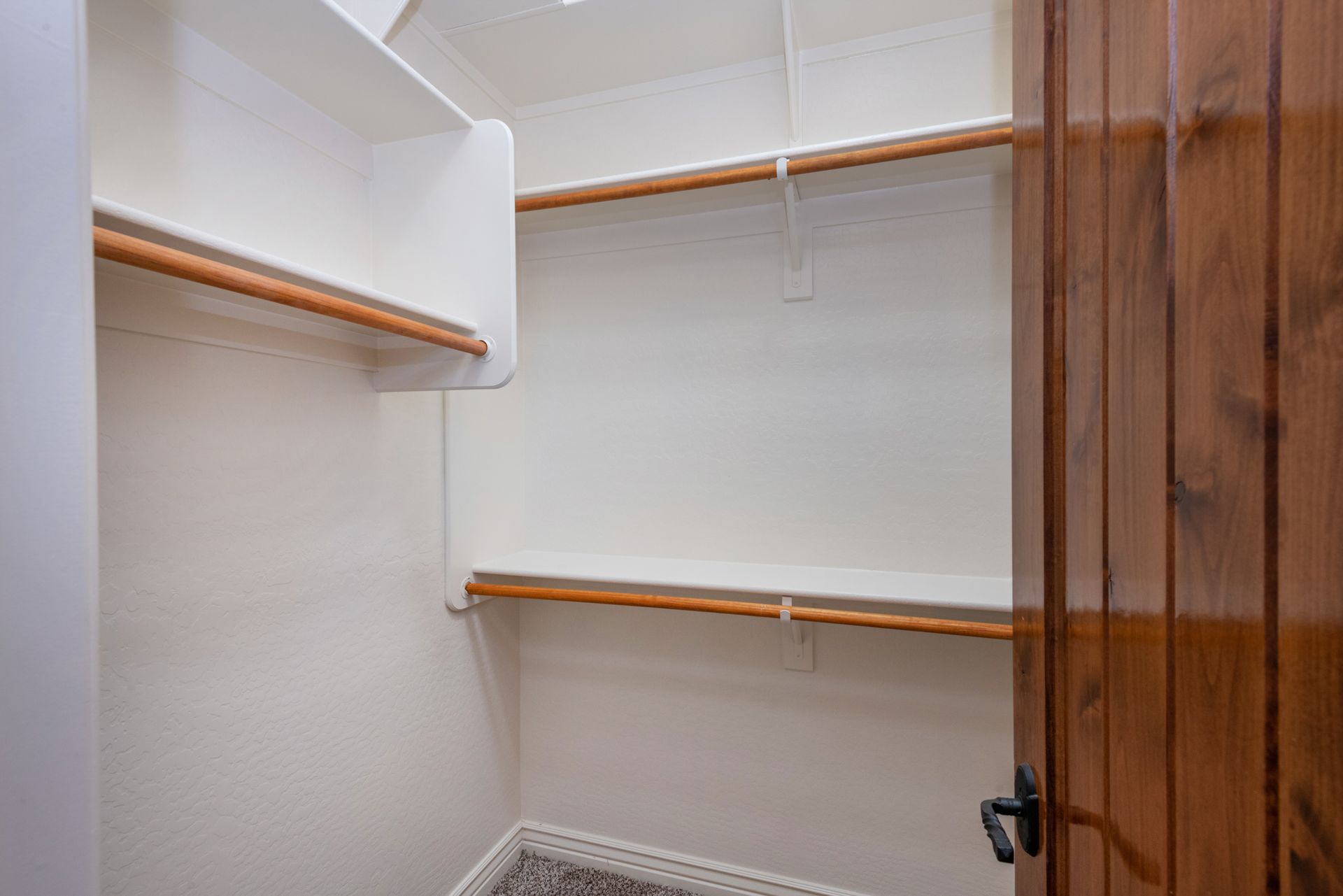 A walk in closet with wooden shelves and a wooden door.