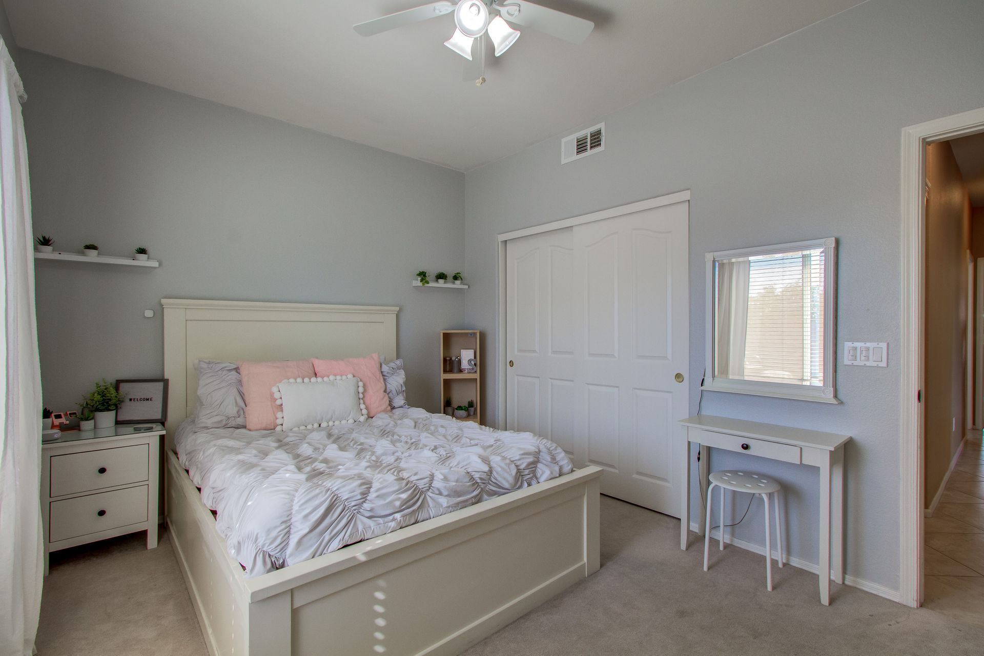 A bedroom with a bed , dresser , mirror and closet.